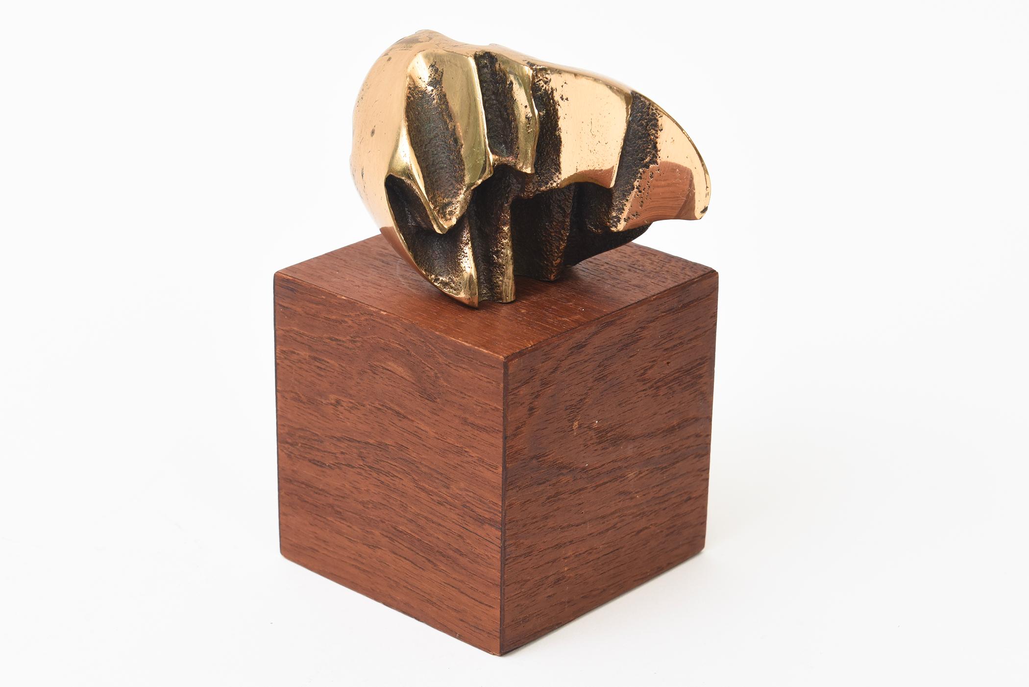 Esta pequeña escultura íntima vintage de latón/bronce y madera es abstracta. En la base de madera hay una marca de V. Se desconoce el escultor o artista. La parte superior se desprende de la base al asentarse sobre un poste de la madera.  La forma