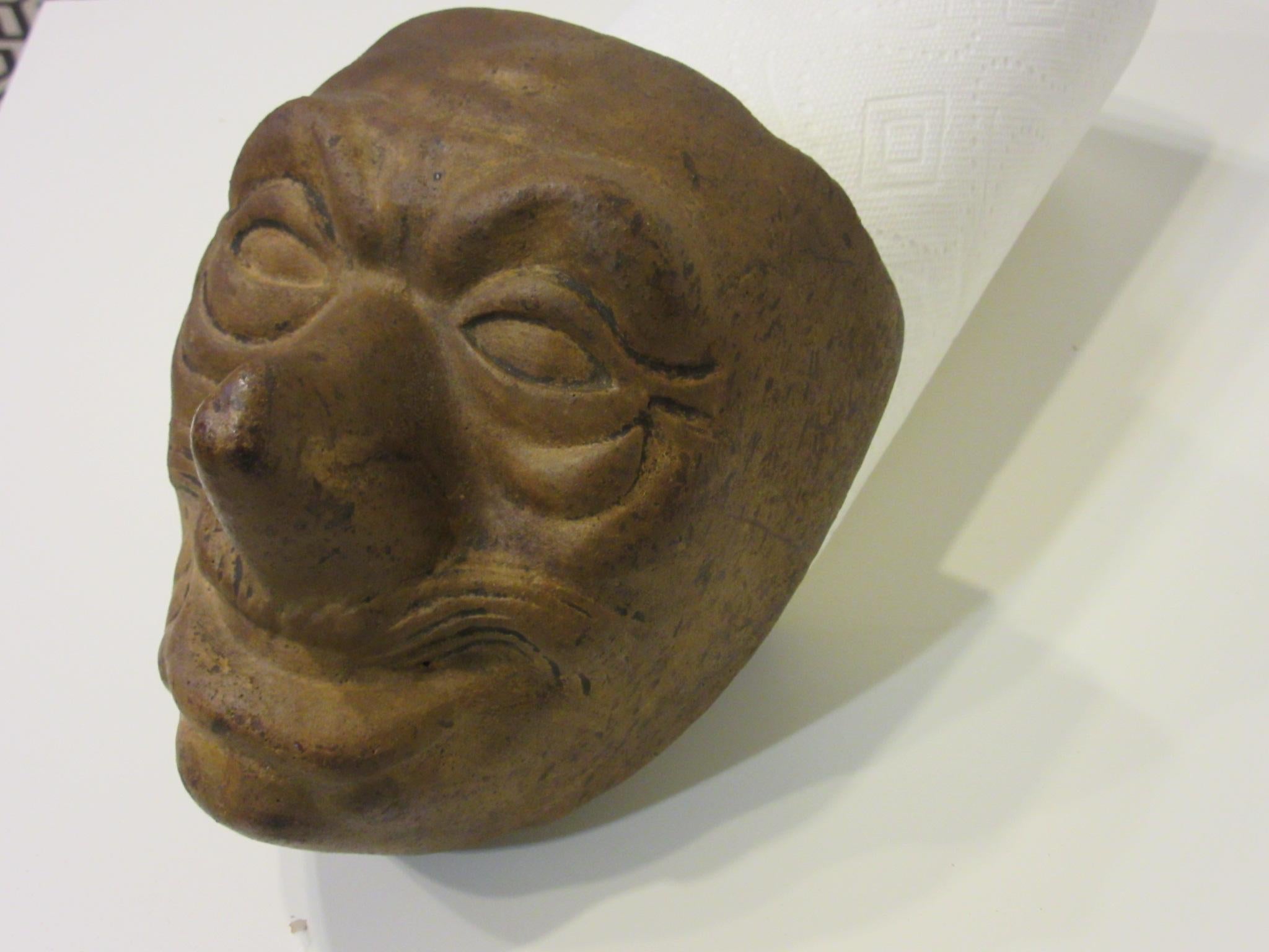 A handcrafted 1920s fired brick mask mold used in making gauze styled Halloween masks by wrapping the mold, hand painting the face and waxing the front and back after drying to set the piece for wearing. This was an early method in mask making and