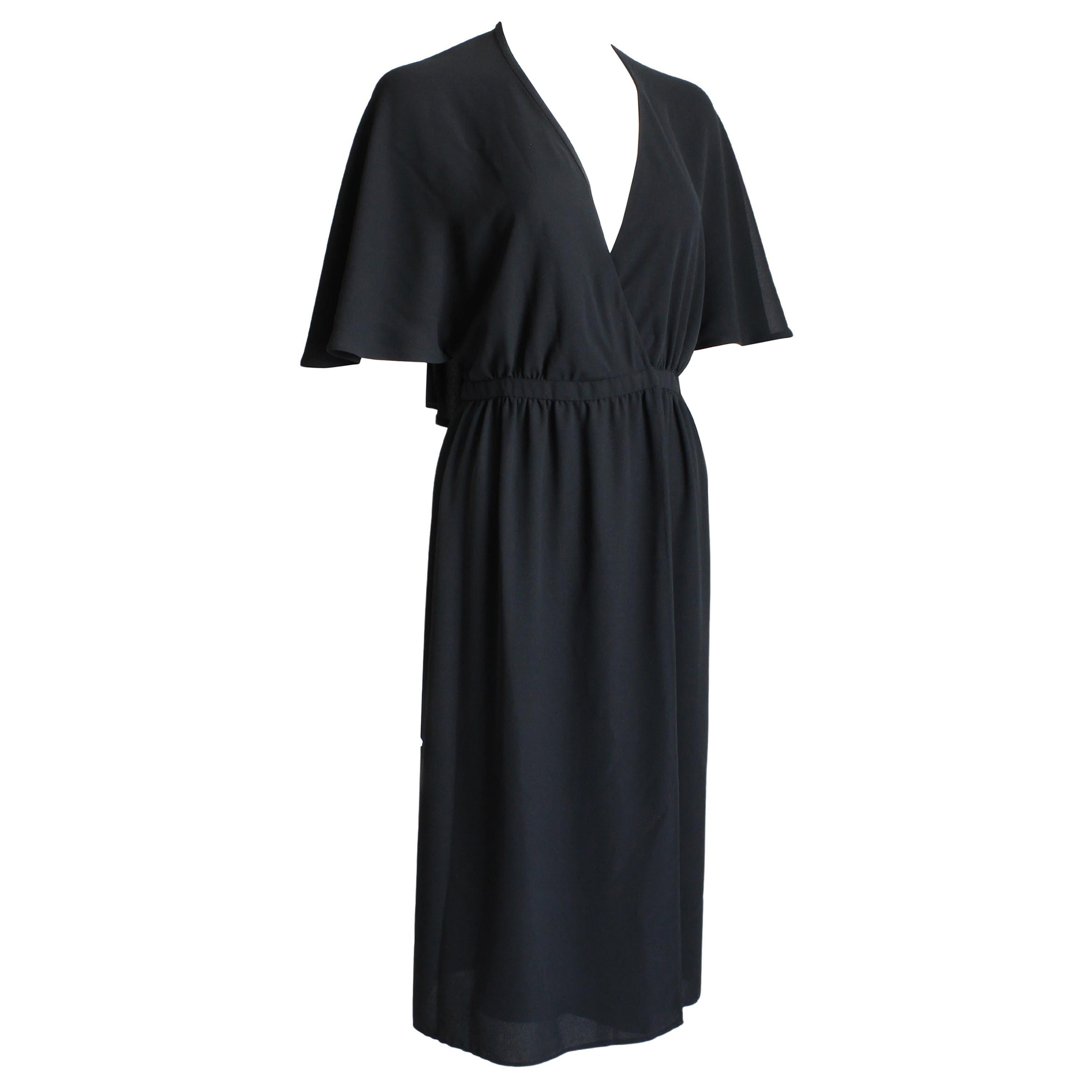Fabulous vintage Halston evening or cocktail dress, likely made in the 1970s. This chic little black dress is made from gorgeous black silk, and features a halter top with an attached flowing capelet. A true wrap dress, it fastens at the waist with