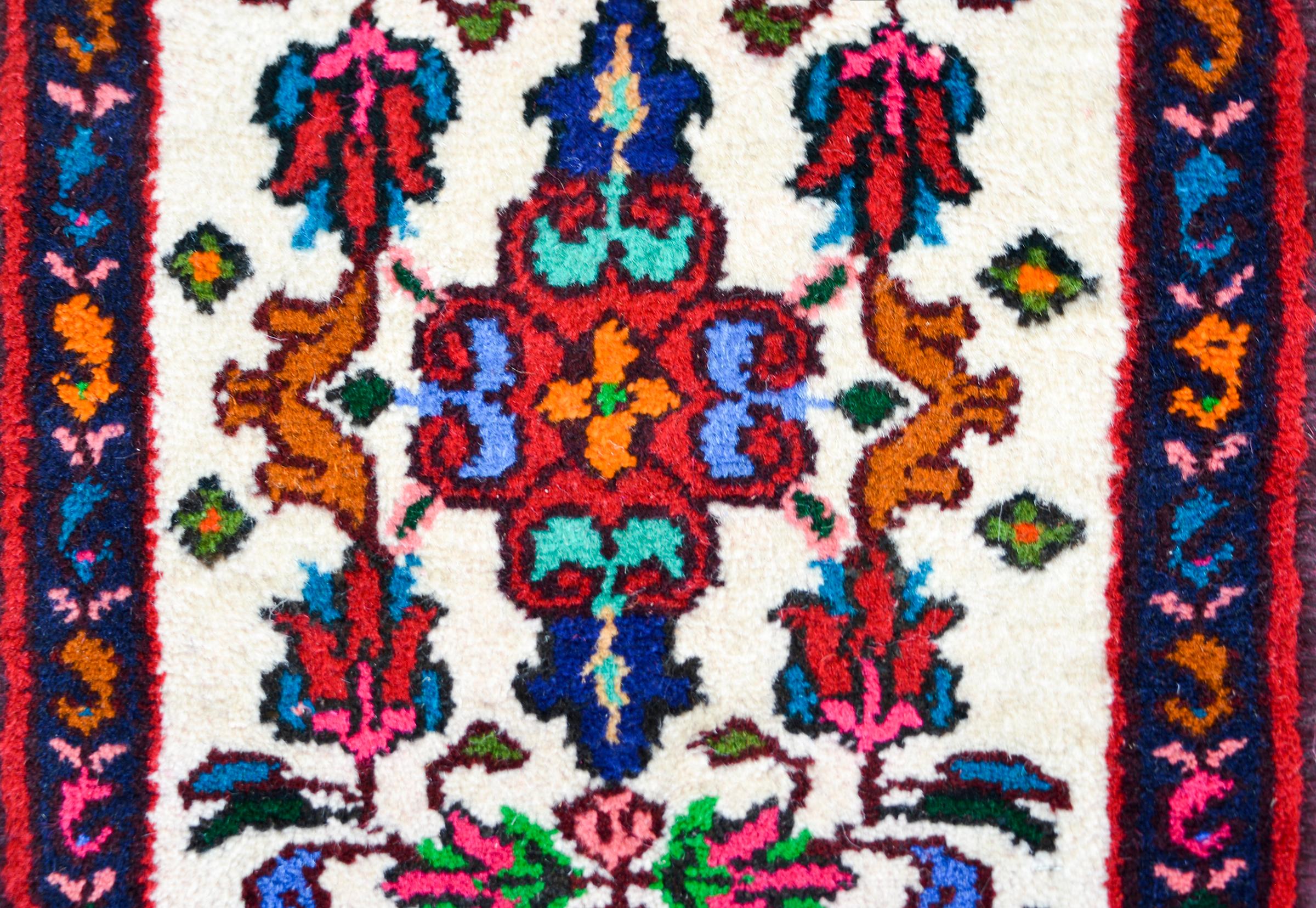 Un tappeto persiano Hamadan vintage con un brillante motivo floreale multicolore su sfondo bianco, circondato da un bordo complementare.