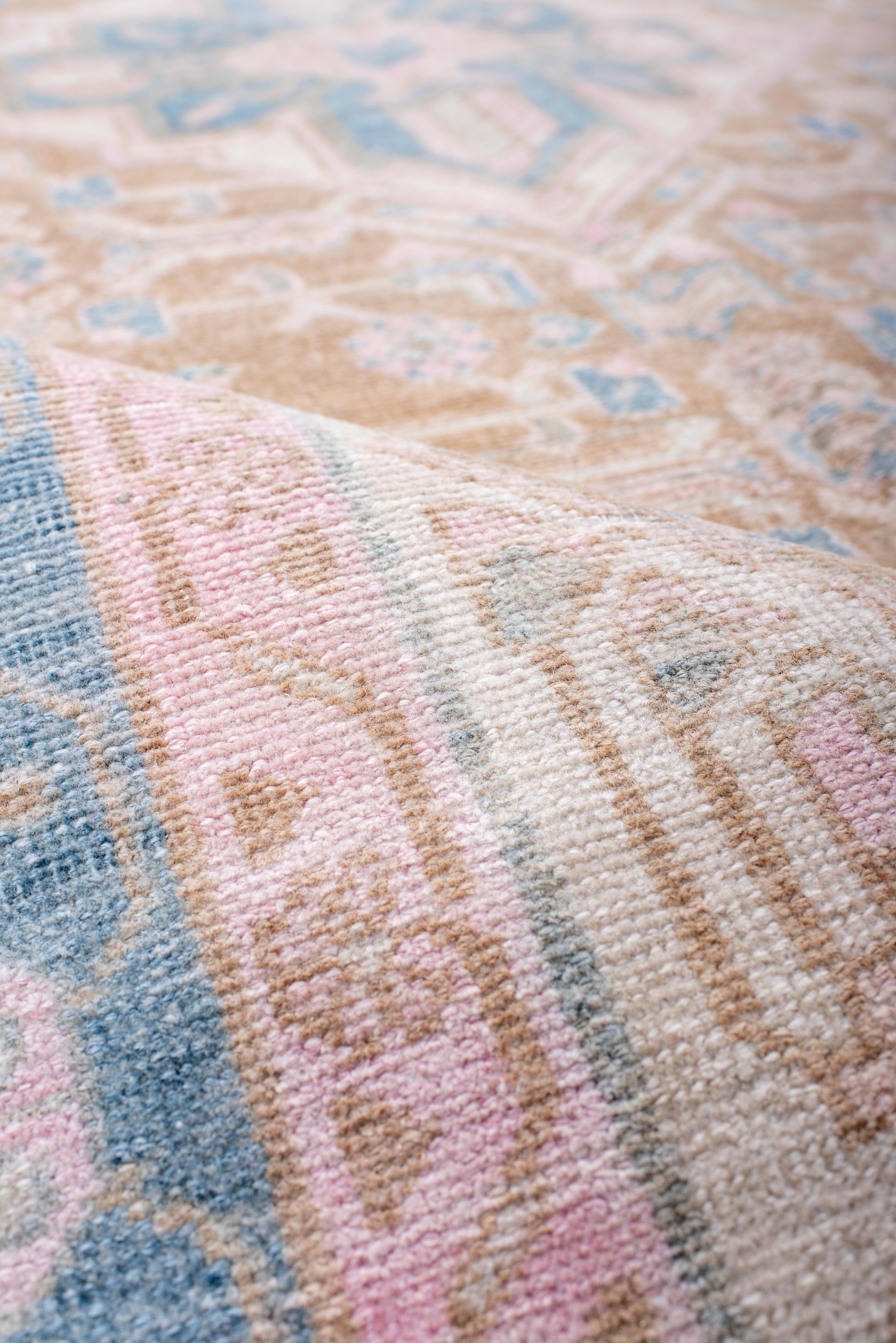 Esta alfombra Hamadan vintage deleita con su delicado diseño de medallones y esquinas, articulado en una serena paleta de rosa polvoriento, arena descolorida y azul cielo. El medallón floral central ancla un campo simétrico de celosías estilizadas,