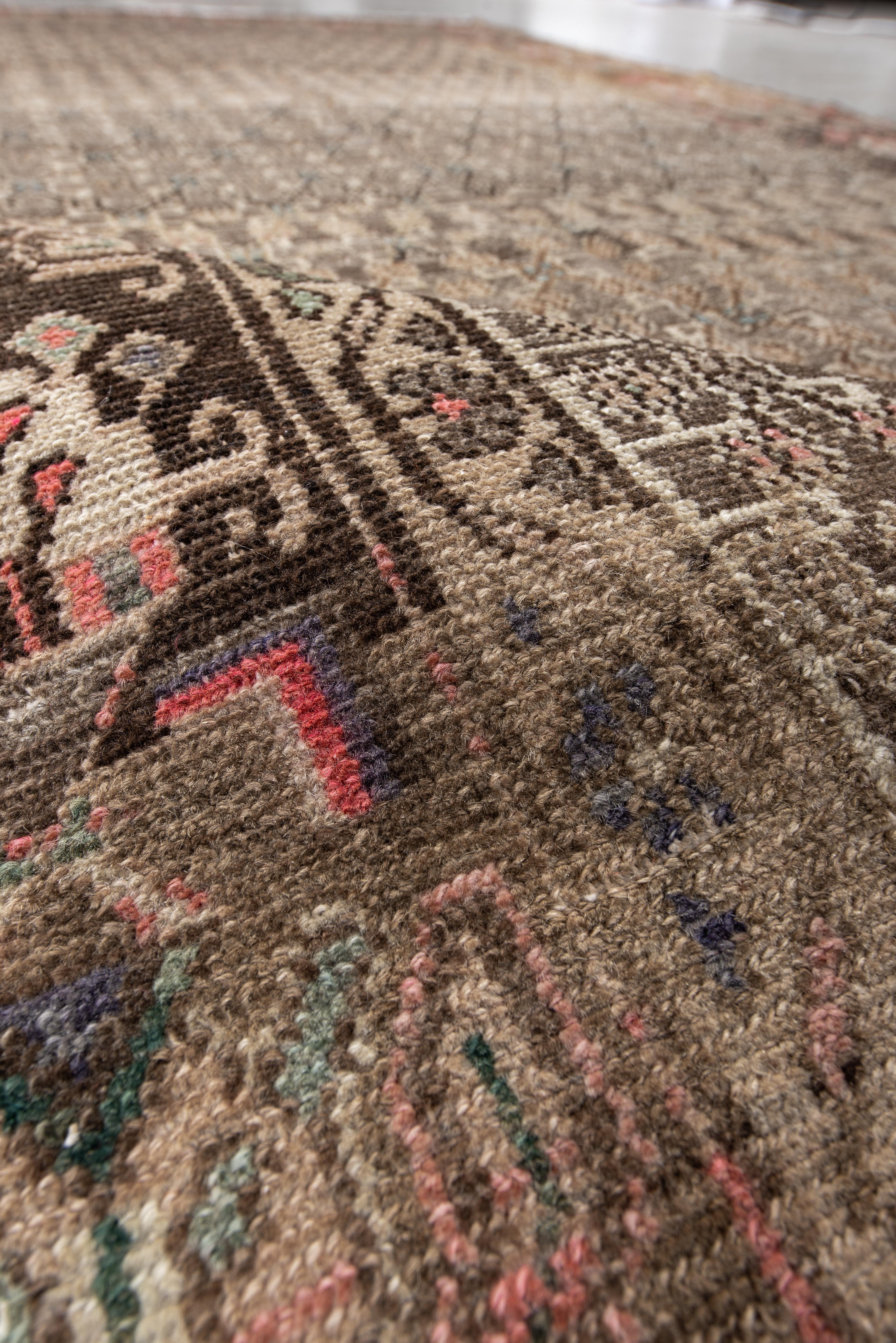 This vintage Hamadan rug features a densely patterned mocha-toned field layered with an intricate lattice of diamonds and subtle floral elements in sand, grey, and walnut hues. The striking wide border introduces a stylized array of blooming