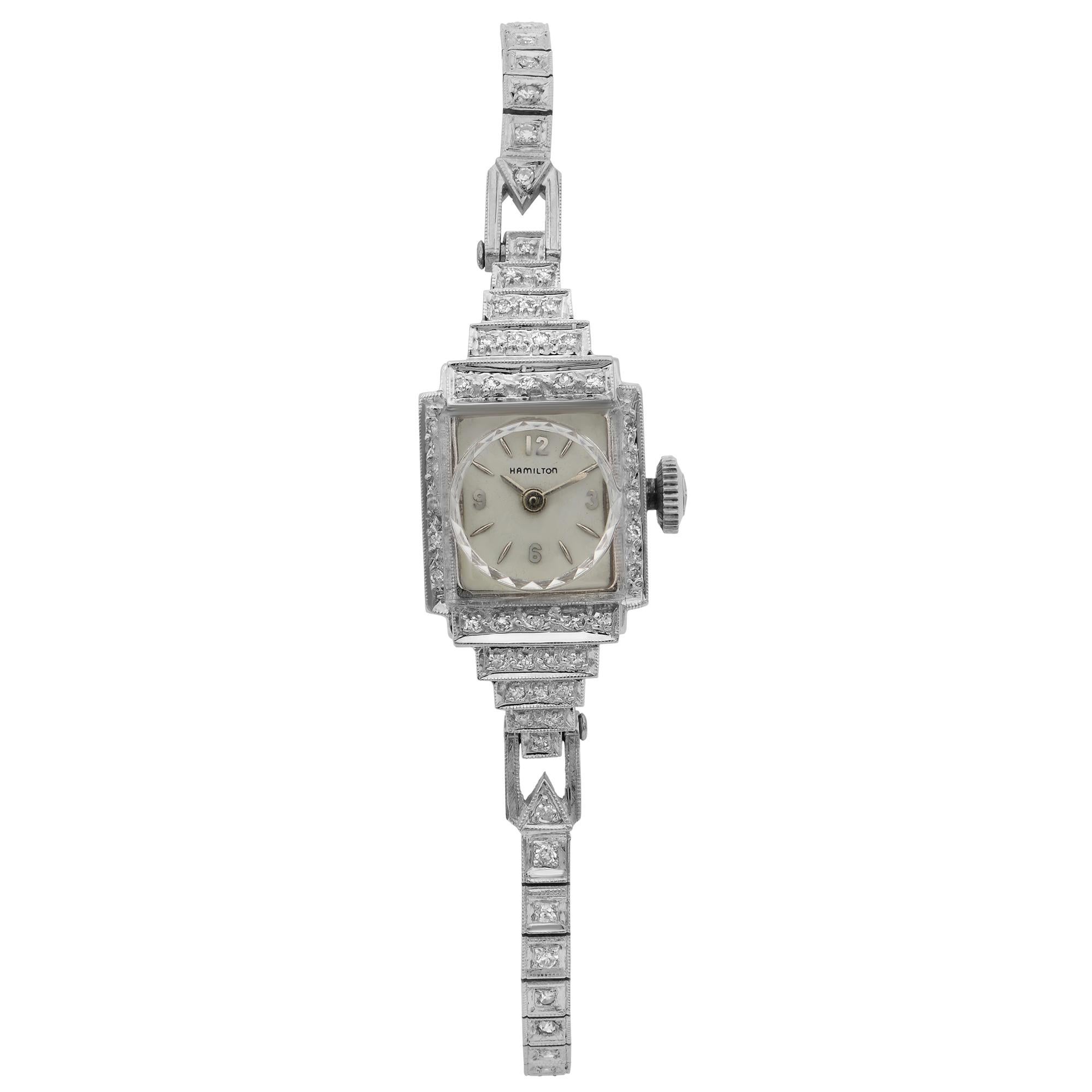This pre-owned Vintage Hamilton 14 Karat White Gold Silver Dial Quartz Ladies' timepiece is powered by quartz (battery) movement which is cased in a white gold case. It has a square shape face, no features dial, and has hand sticks & numerals style