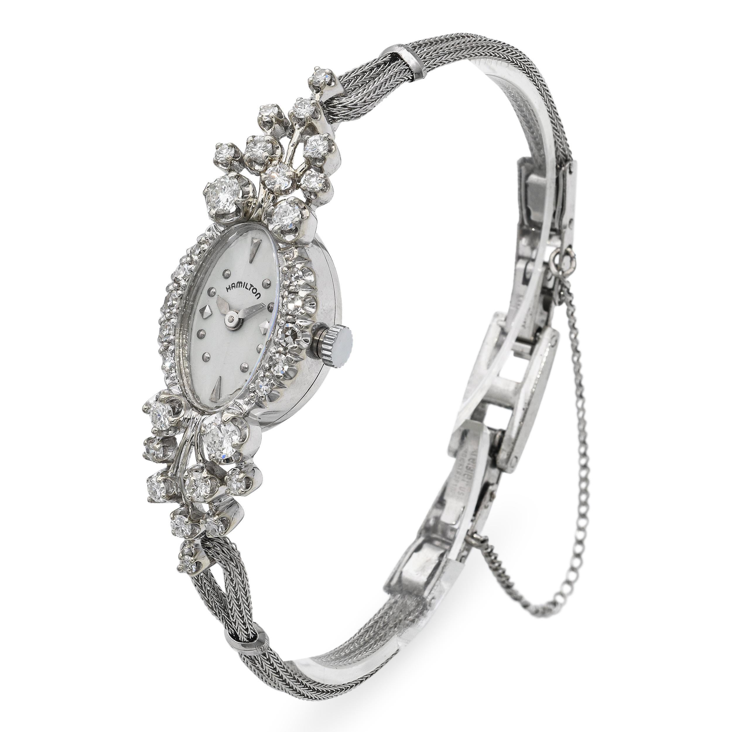 Diese elegante Hamilton Damenuhr im Vintage-Stil ist aus massivem 14-karätigem Weißgold gefertigt und mit funkelnden Diamanten auf der Lünette und den Bandanstößen verziert. Das Gehäuse beherbergt ein klassisches, silberfarbenes Zifferblatt mit