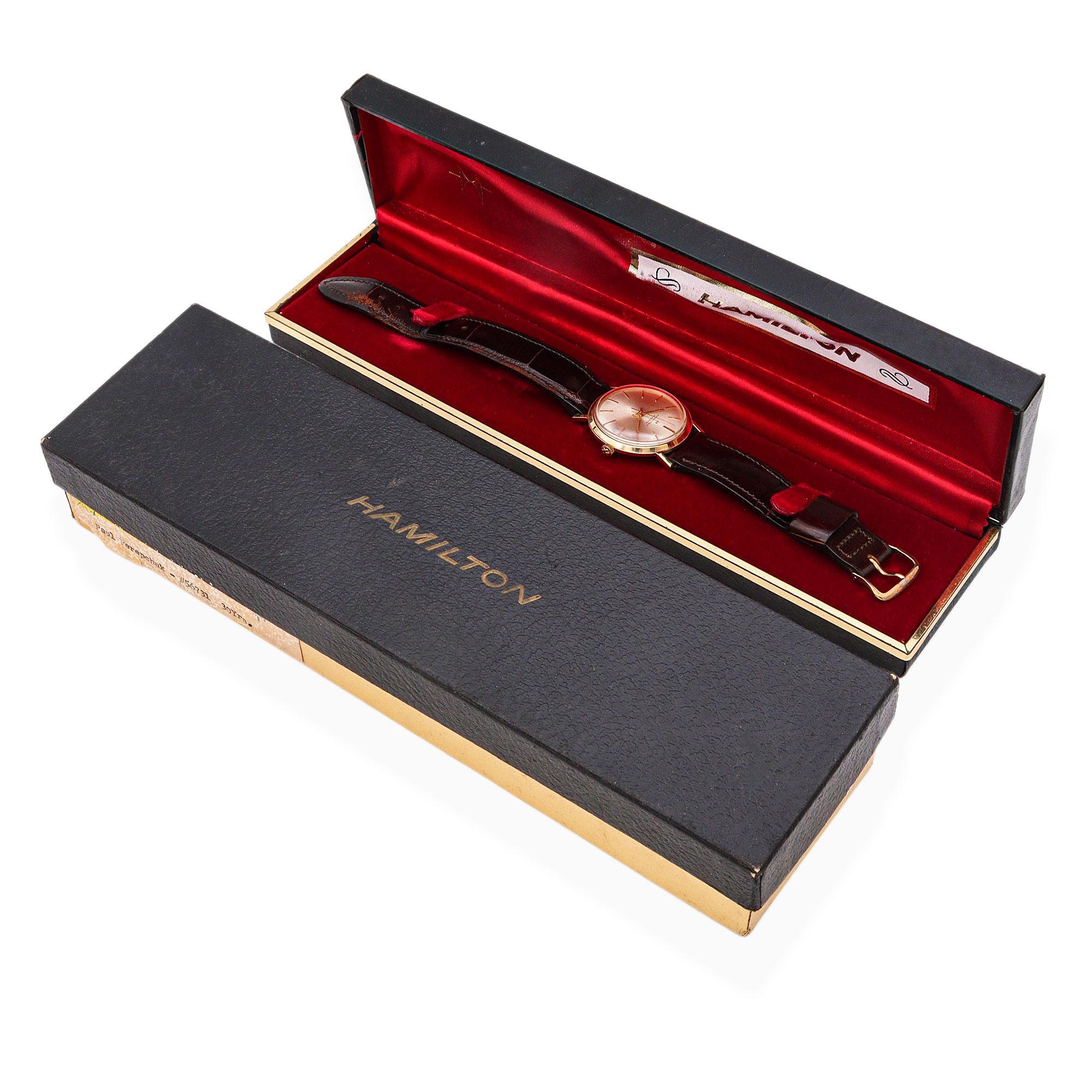 Expresión por excelencia de la elegancia de mediados de siglo, este Reloj Hamilton Vintage Masterpiece para hombre es un verdadero testimonio de la herencia relojera estadounidense. Fabricada en oro amarillo macizo de 14 quilates, la caja redonda
