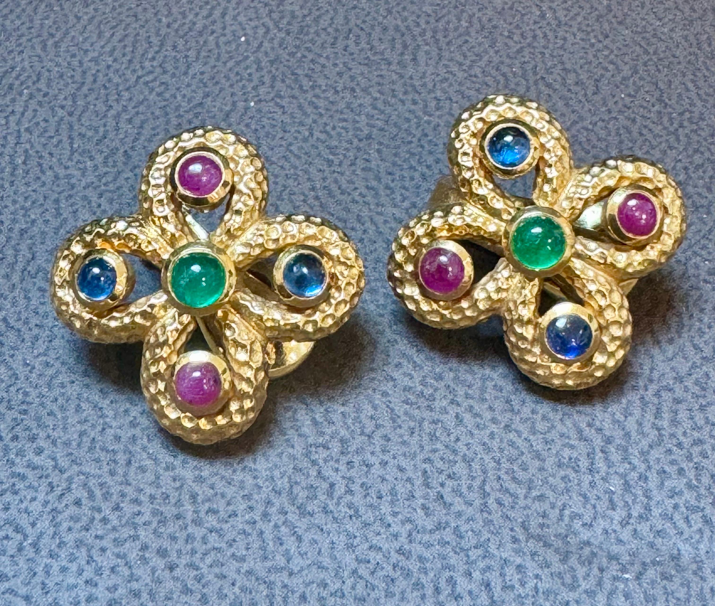 Ti presentiamo gli orecchini a trifoglio in oro 18 carati martellato vintage, con squisiti dettagli di rubini, zaffiri e smeraldi cabochon, realizzati dal famoso designer David Webb. Questi splendidi orecchini sono realizzati in oro giallo 18