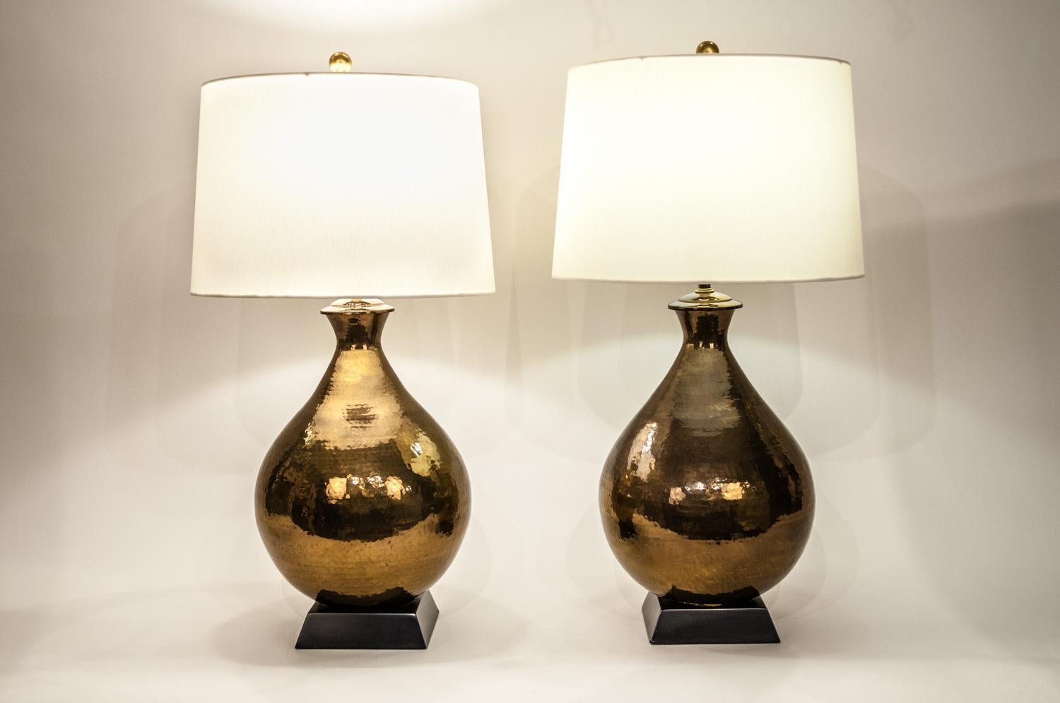 Vintage Hammered Brass pair table / task lamps with wood black base. Each lamp is in excellent working condition. Each lamp come with round drum shade. Each lamp measure 35 inches high from base to top of fenial x 14.5 inches diameter. The wood base