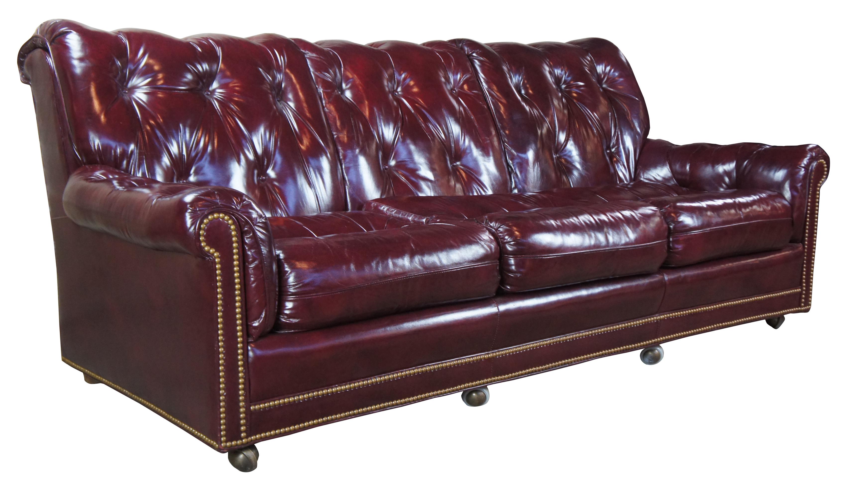 Vintage Hancock & Moore top grain leather sofa. Features a burgundy or dark red tufted leather and plush rolled back with brass nailhead trim, circa 1980s. On castors for ease of movement. Measure: 87
