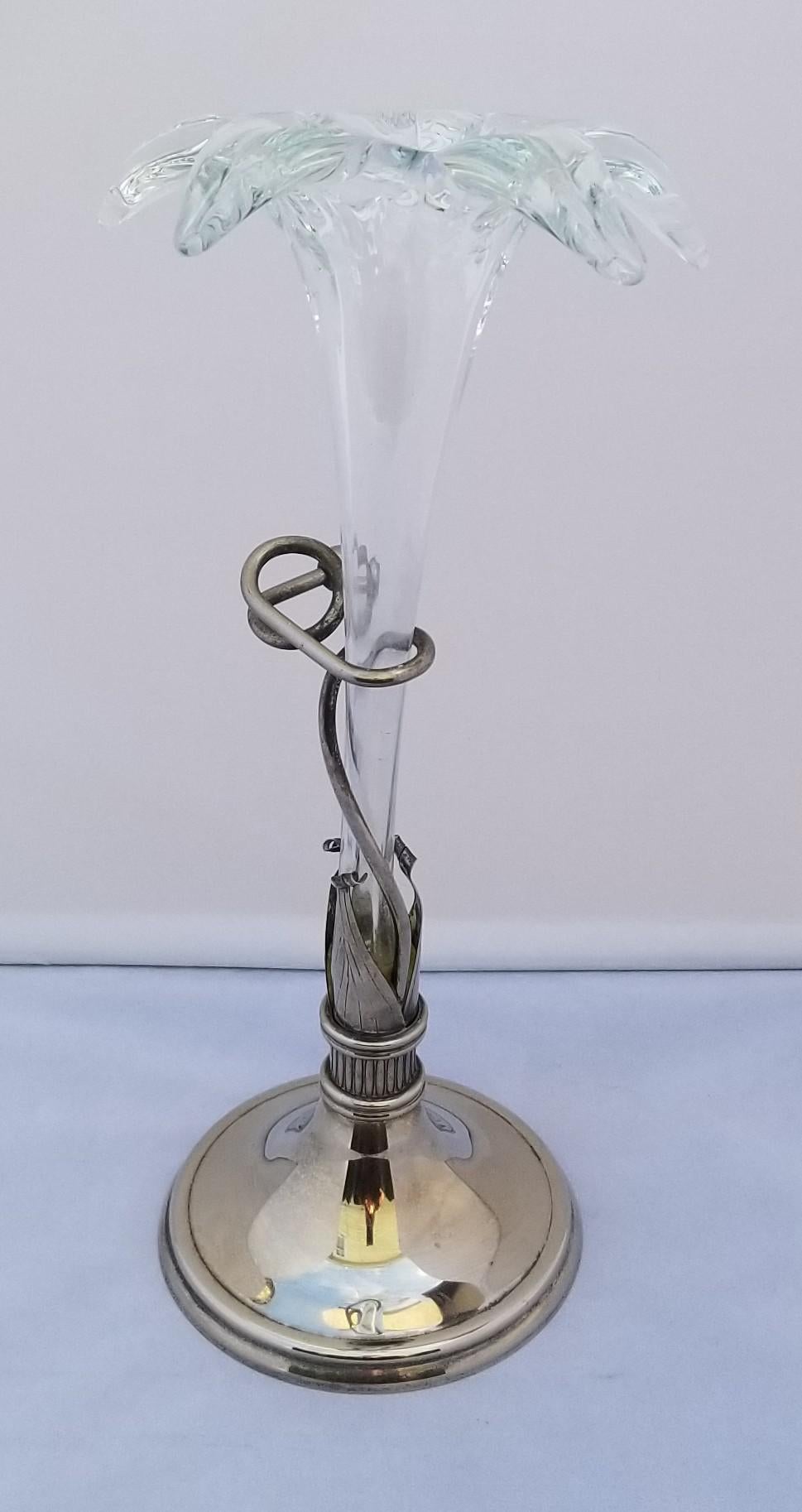 A rare beauty with intricate hand-blown glass in the shape of a lily, a silver or silver plated base with tendrils gently cradling the stem of the flower. This vase is likely from the 1980s, but is clearly heavily influenced by the art nouveau