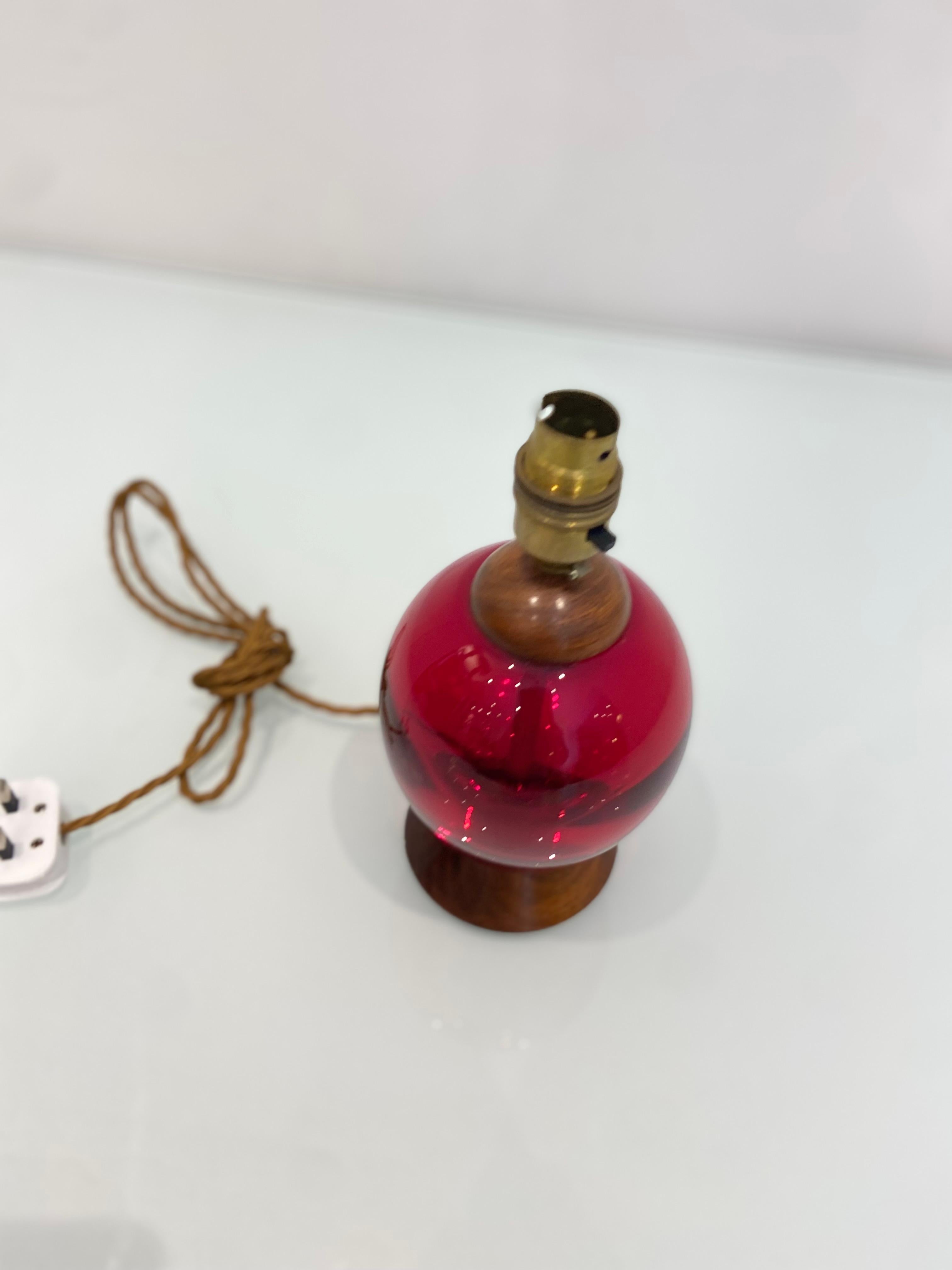 Une lampe de table unique en verre soufflé à la main de couleur rouge. 

Fabriqué dans un verre coloré qui attire le regard, il complète et contraste magnifiquement avec les accents en bois.

Récemment, le câblage a été refait avec une prise de