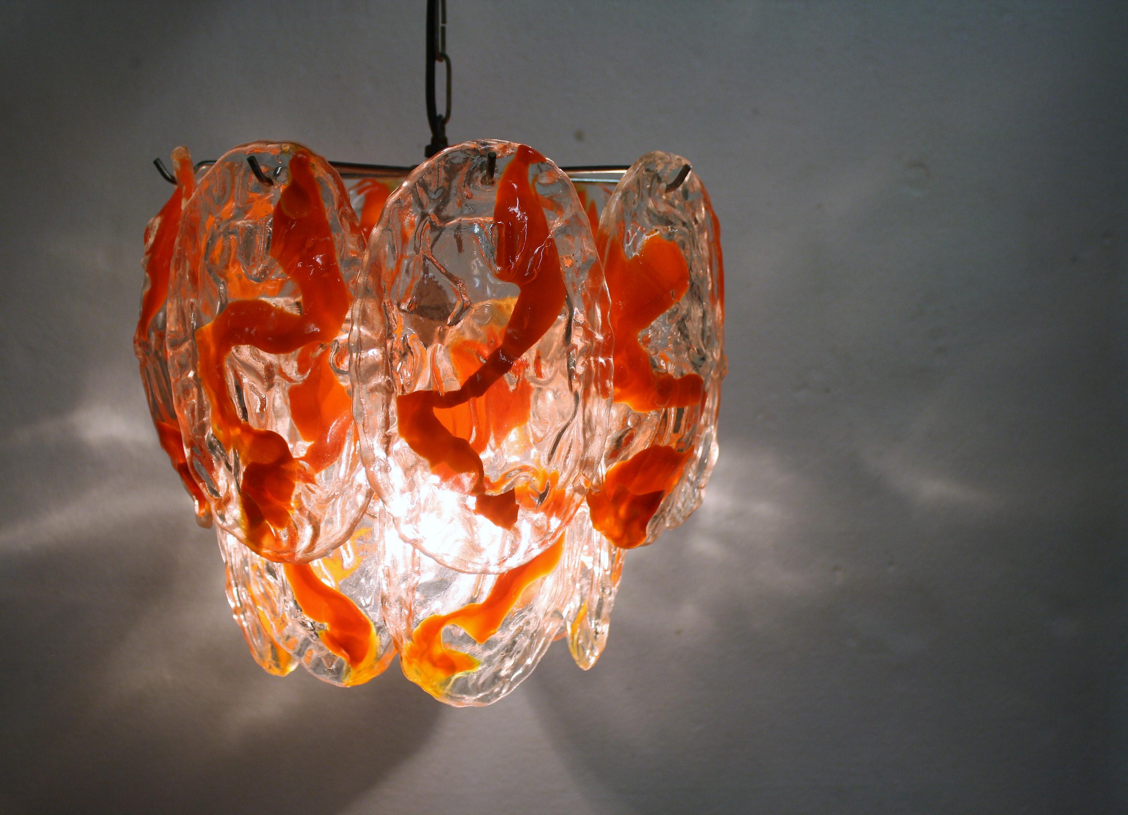 Magnifique lustre en verre de Murano soufflé à la main par La Murrina.

Le lustre est composé de 14 verres soufflés à la main avec un décor orange.

Il comporte un point lumineux E26/E27.

Testé et prêt à l'emploi.

Bon état, tous les verres