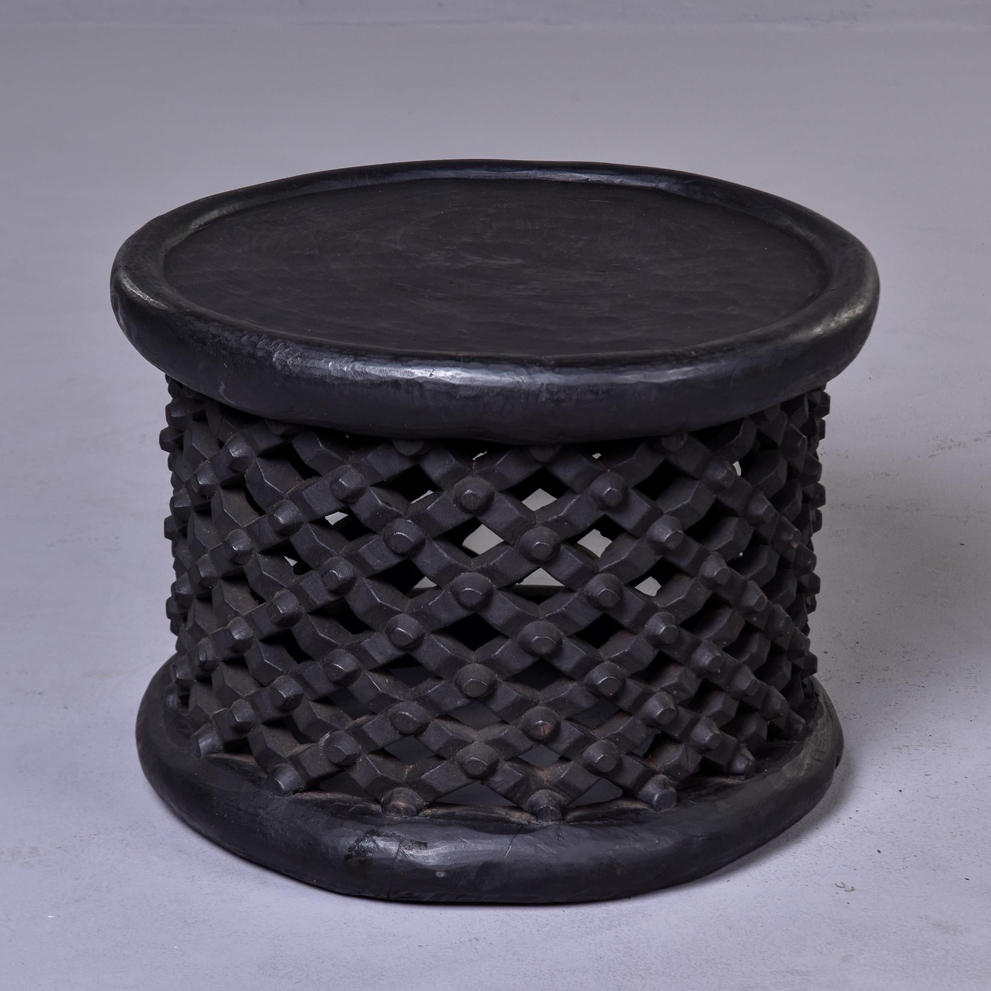 Circa 1980s round dark wood stool or side table. Hand-carved by a tribal artist in Cameroon, this style is known as a spider stool because of its knobby web-like base. The Bamileke people see spiders as a link between the living and the dead and
