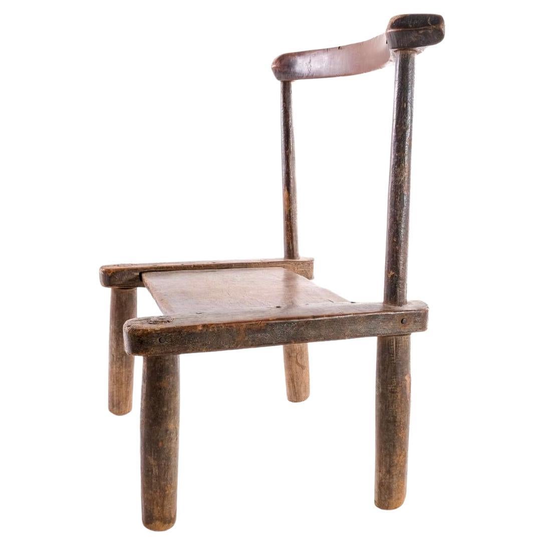 Vintage hand carved African Baule Tribal yoke back low chair.  Vintage hand carved African Baule Triball chair. Low chairs such as this were carried on the shoulders of village men as they went to attend social gatherings or community rituals in the