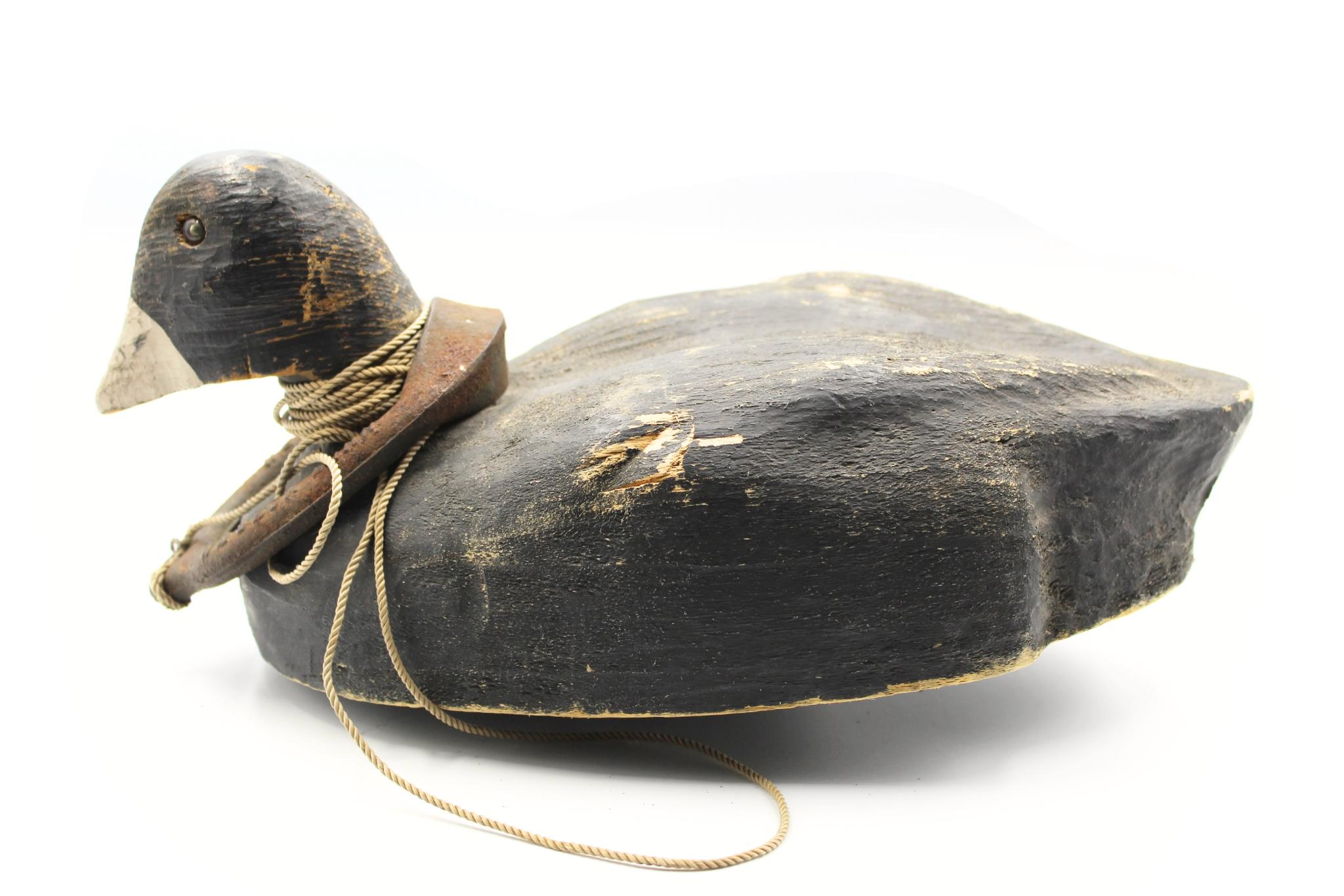 Il s'agit d'un leurre en bois original du 20e siècle, sculpté et peint à la main. Le leurre a une tête blanche en flèche avec des yeux en verre. Son dos, sa poitrine et son ventre sont peints en noir uni. Une ligne de leurre en corde et un poids en