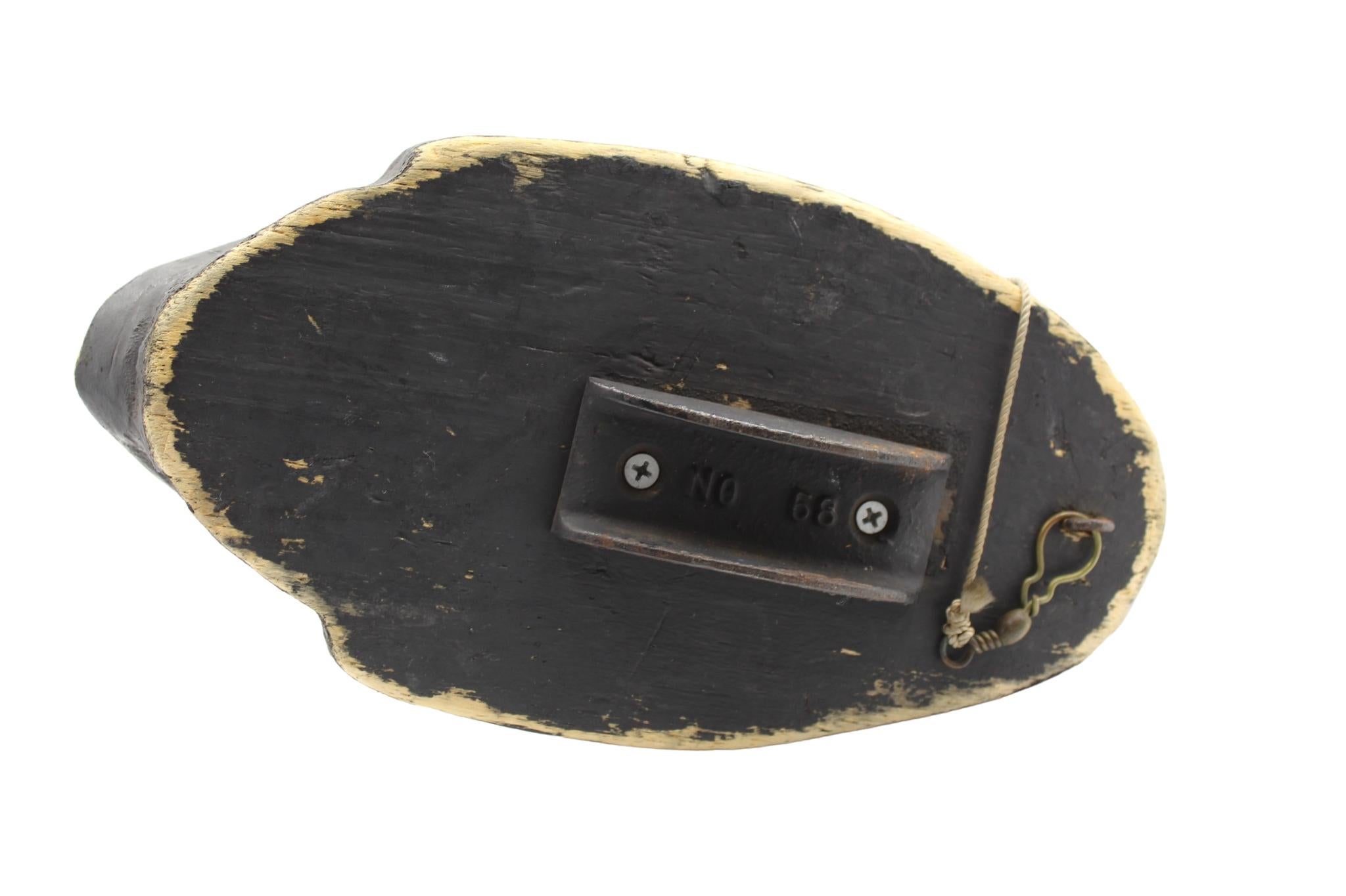 Il s'agit d'un leurre en bois original du 20e siècle, sculpté et peint à la main. Le leurre a une tête blanche en flèche avec des yeux en verre. Son dos, sa poitrine et son ventre sont peints en noir uni. Une ligne de leurre en corde et un poids en