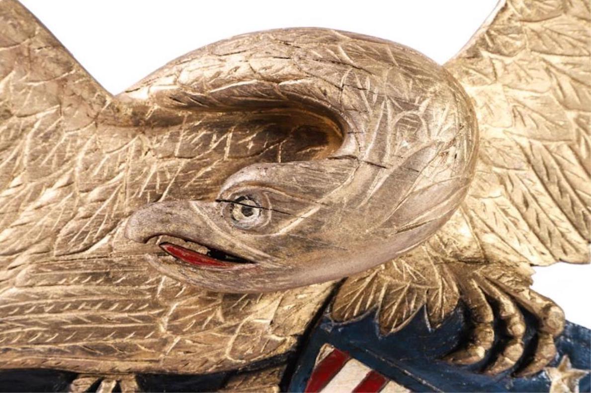 This is a hand carved and painted American folk eagle in the style of John Bellamy. The eagle has spread wings and its head turned to its right. The artist, unknown, carved the eagle with exceptional detail, especially in the eagle's wings.

The