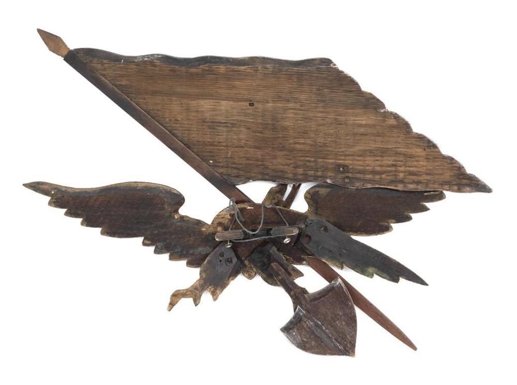 Presented is an antique hand carved eagle by George Strapf. Painted and parcel-gilded, this wood eagle is a stellar example of American Folk Art at the turn of the 20th century. The eagle clutches a shield in its dexter talon and supports an