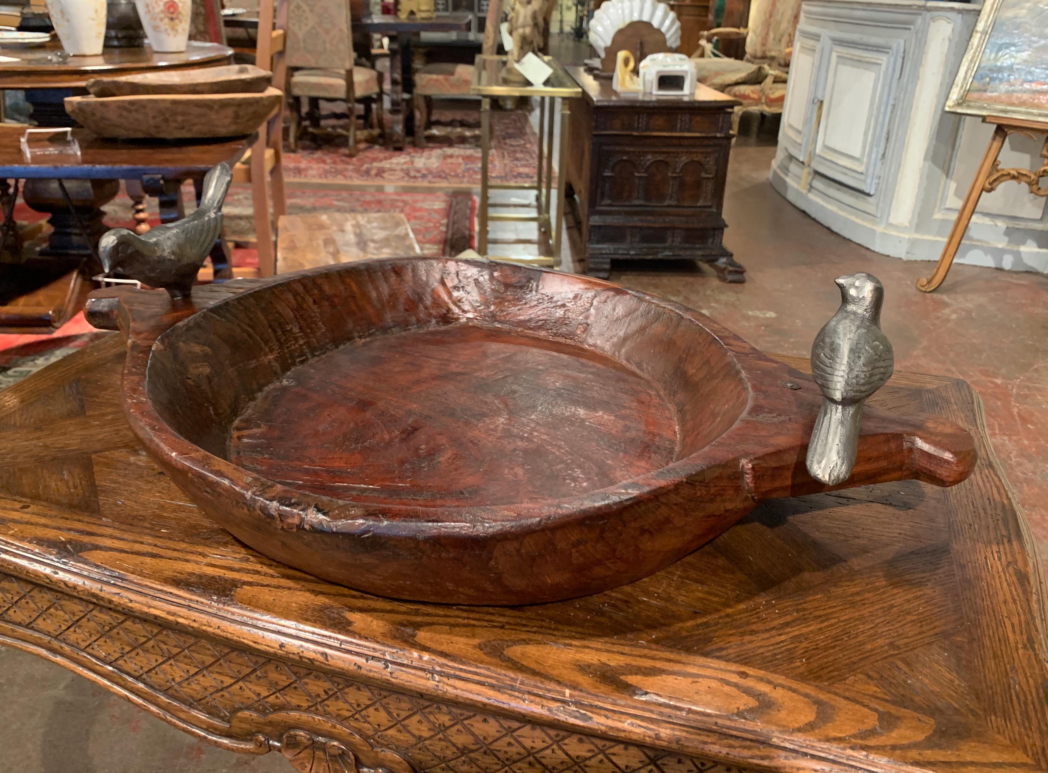 This large fruit or vegetable bowl was created circa 1990, round in shape with side handles, the chestnut dish is hand carved and is decorated with two forged and polished iron dove birds standing on top of the handles. The decorative bowl is in