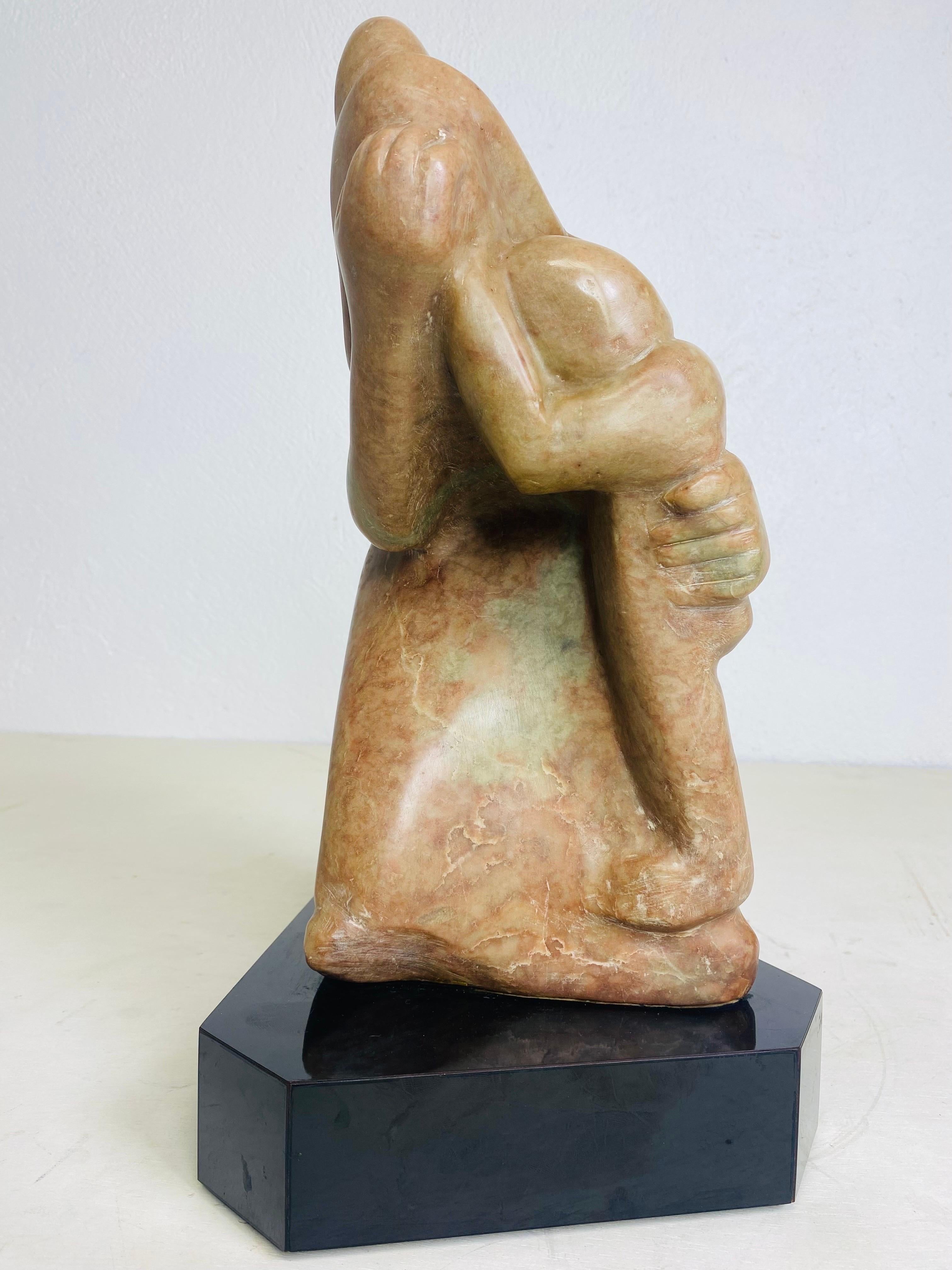 This is a mid century  vintage, modern marble hand carved figural sculpture. The sculpture is a mother and children embracing. This modernist sculpture is presented on a black laminate plinth. The sculpture is artist side on the back lower left-hand