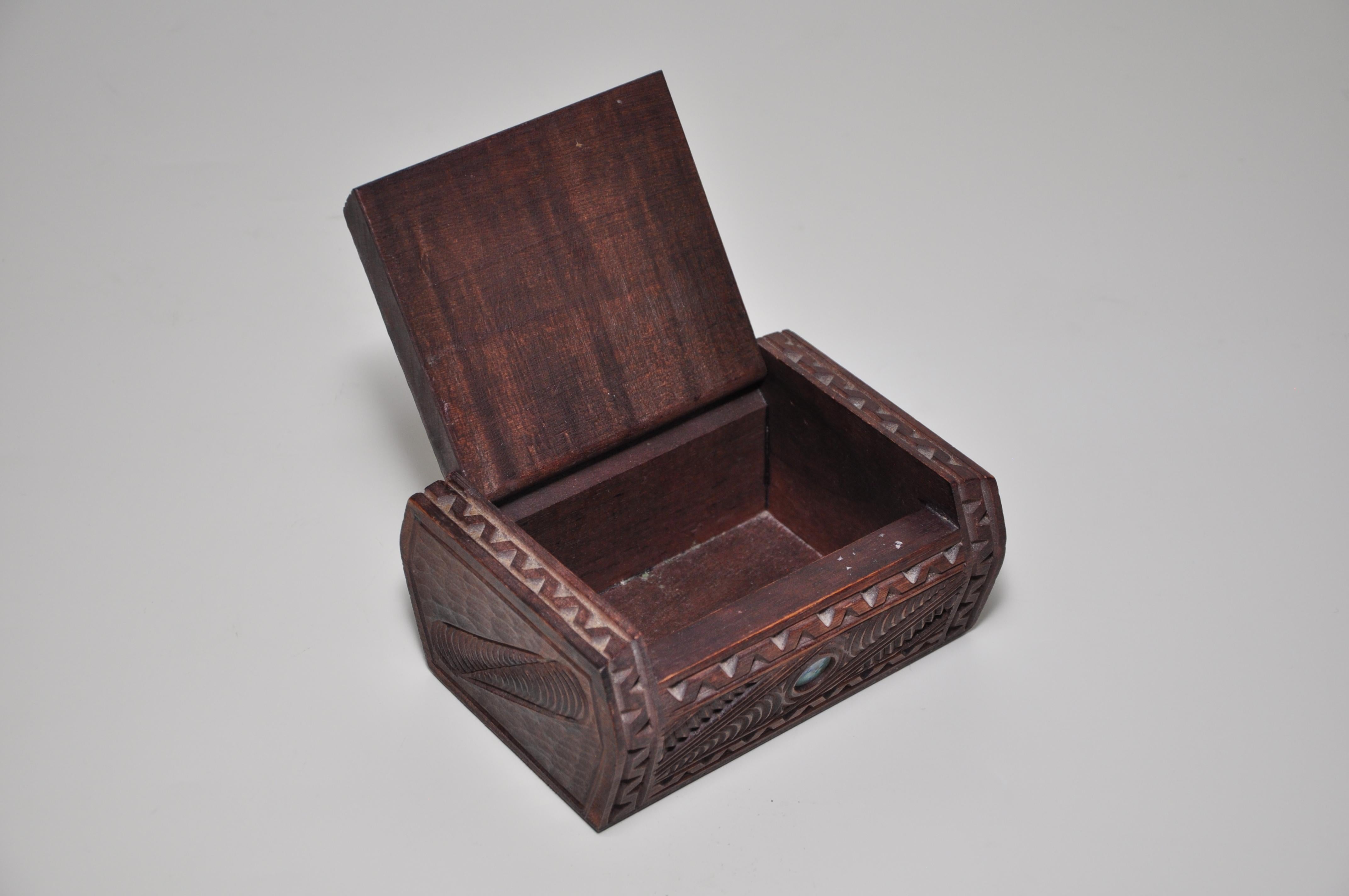 Vintage hand carved Shell Eyes Wooden Box 

A vintage hand carved and inlaid dark wooden trinket or jewelry box decorated with a Maori tribal face and inlaid paua shell ‘eyes’ on the pin-hinged lid, with other incised motifs to the sides. This is