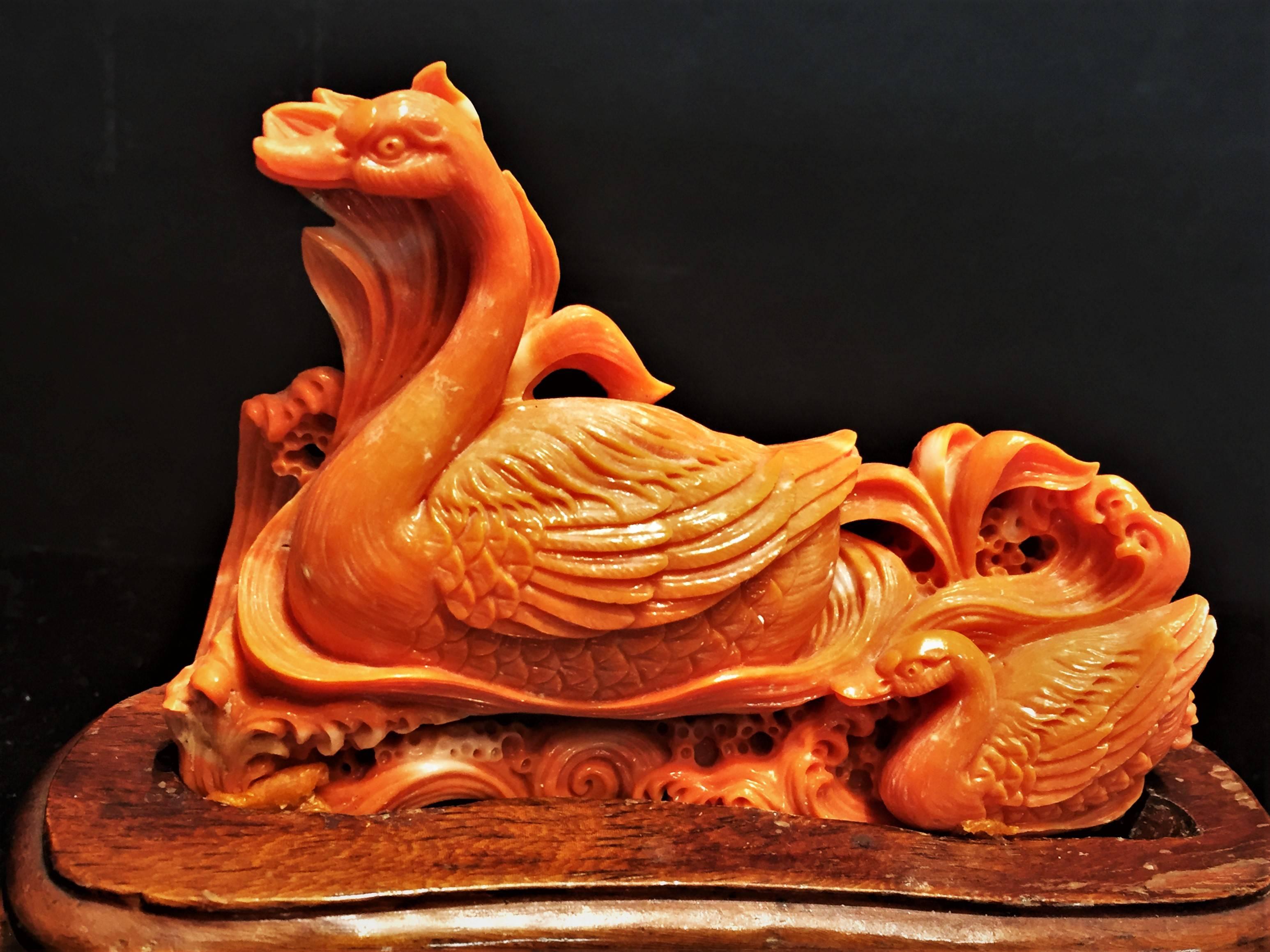 A vintage, beautifully and meticulously hand-carved solid red coral sculpture, depicting a swan mother and a swan-child peacefully gliding across the water among thickets, China, 20th century.
 