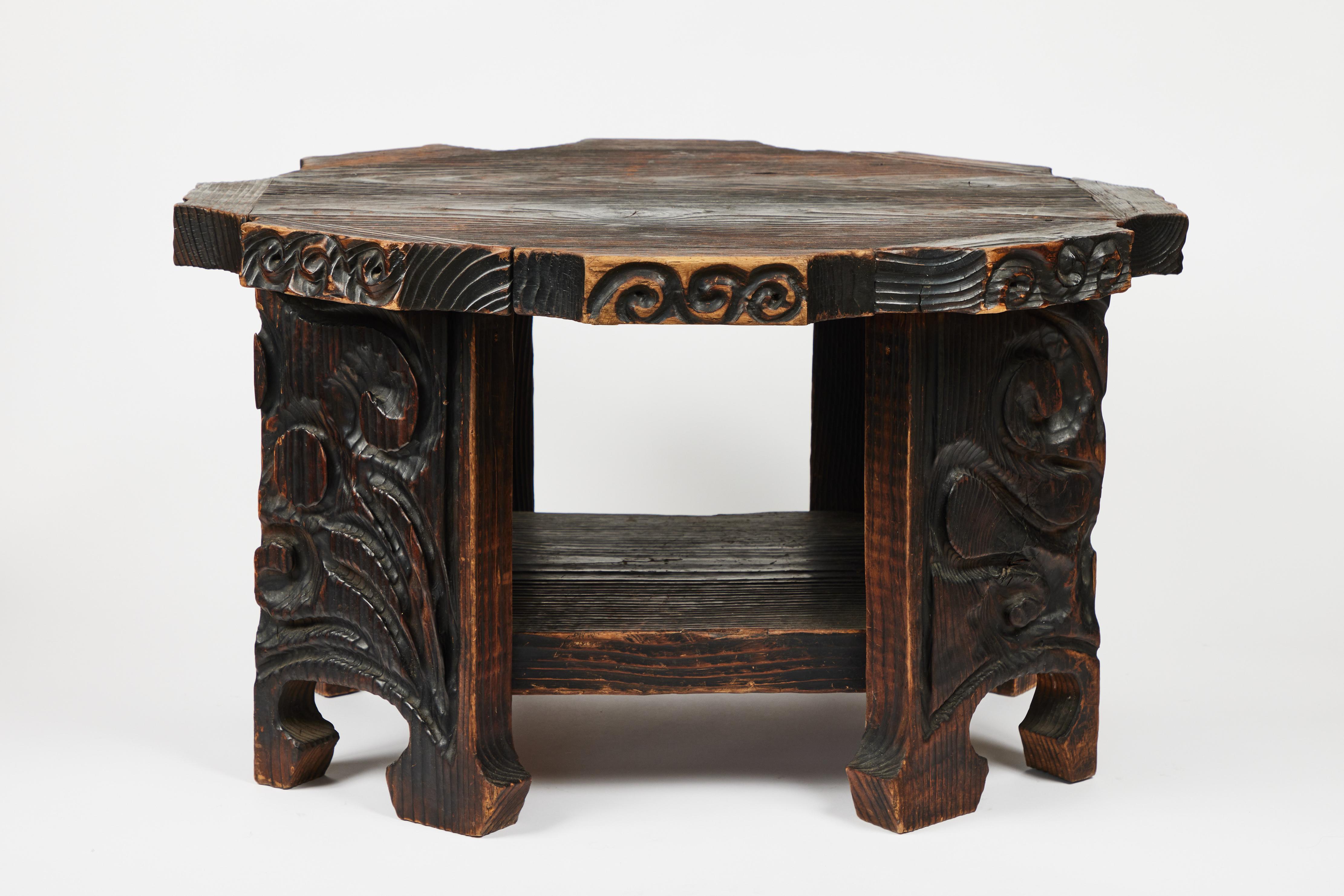 Rustic in design, this vintage hand carved small wood table from Morocco is outstanding. It is constructed and carved from an attractive deep grained wood, has a strong octagonal shaped top and bottom shelf and is that perfect standout piece for