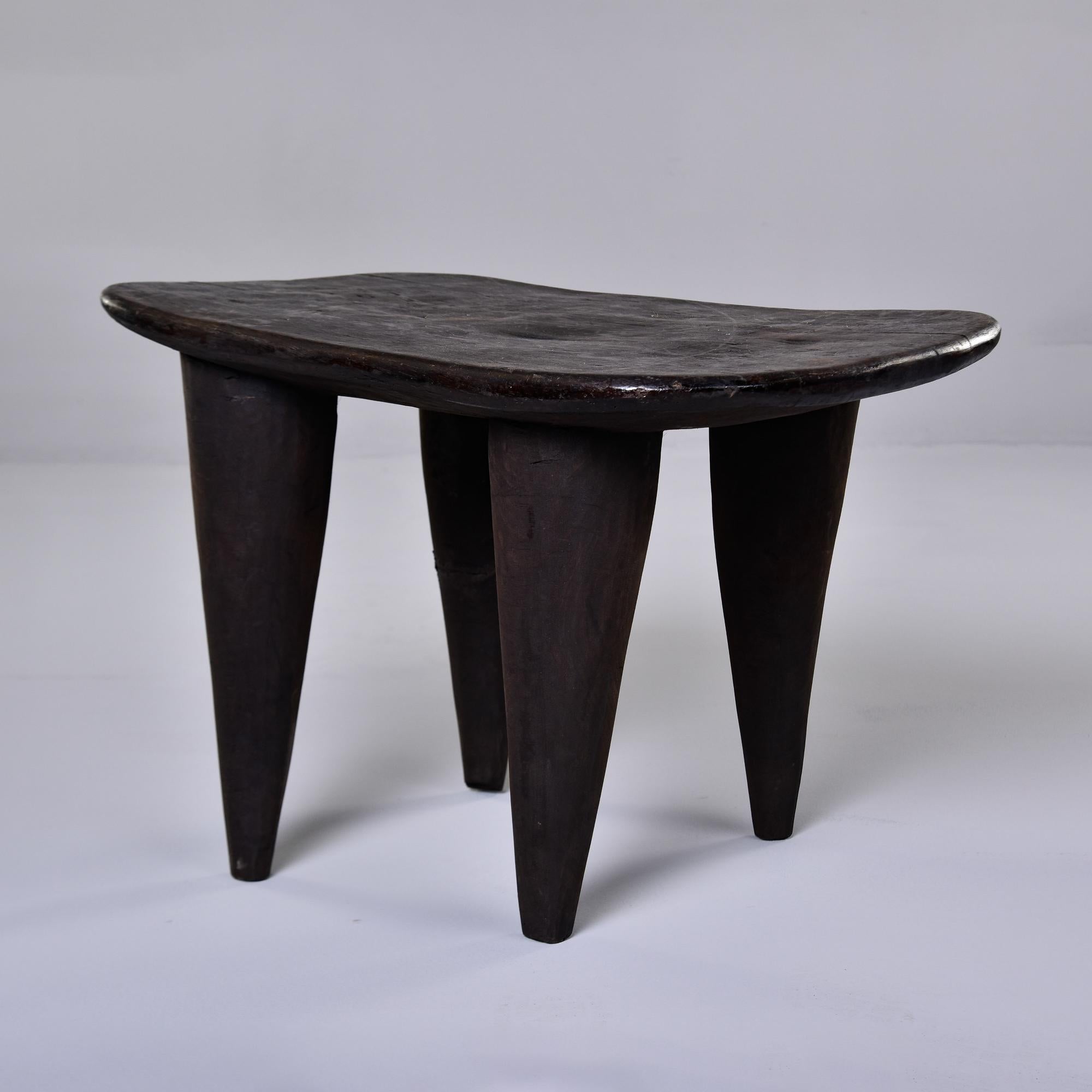 This circa 1980s stool or side table is just under 23” wide. It is hand carved from a single piece of wood with thick, tapered legs by the Senufo people of Cote d’Ivoire. Very distinct and versatile;  this can be used as a stool, ottoman or accent