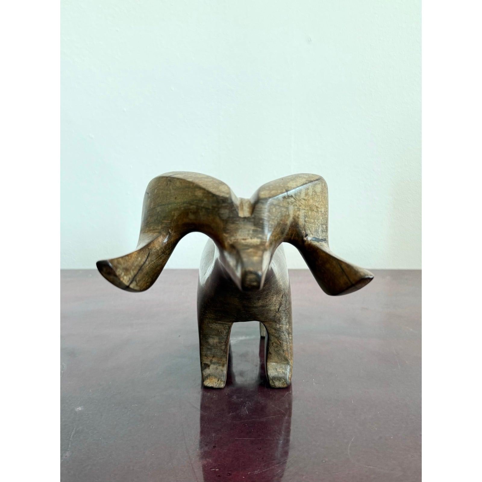 Questo ariete scultoreo in legno vintage è intagliato a mano con curve audaci e stilizzate e una forma forte e compatta. La sua forma astratta evidenzia l'arco drammatico delle corna, bilanciato da un corpo minimale, quasi totemico. Le venature