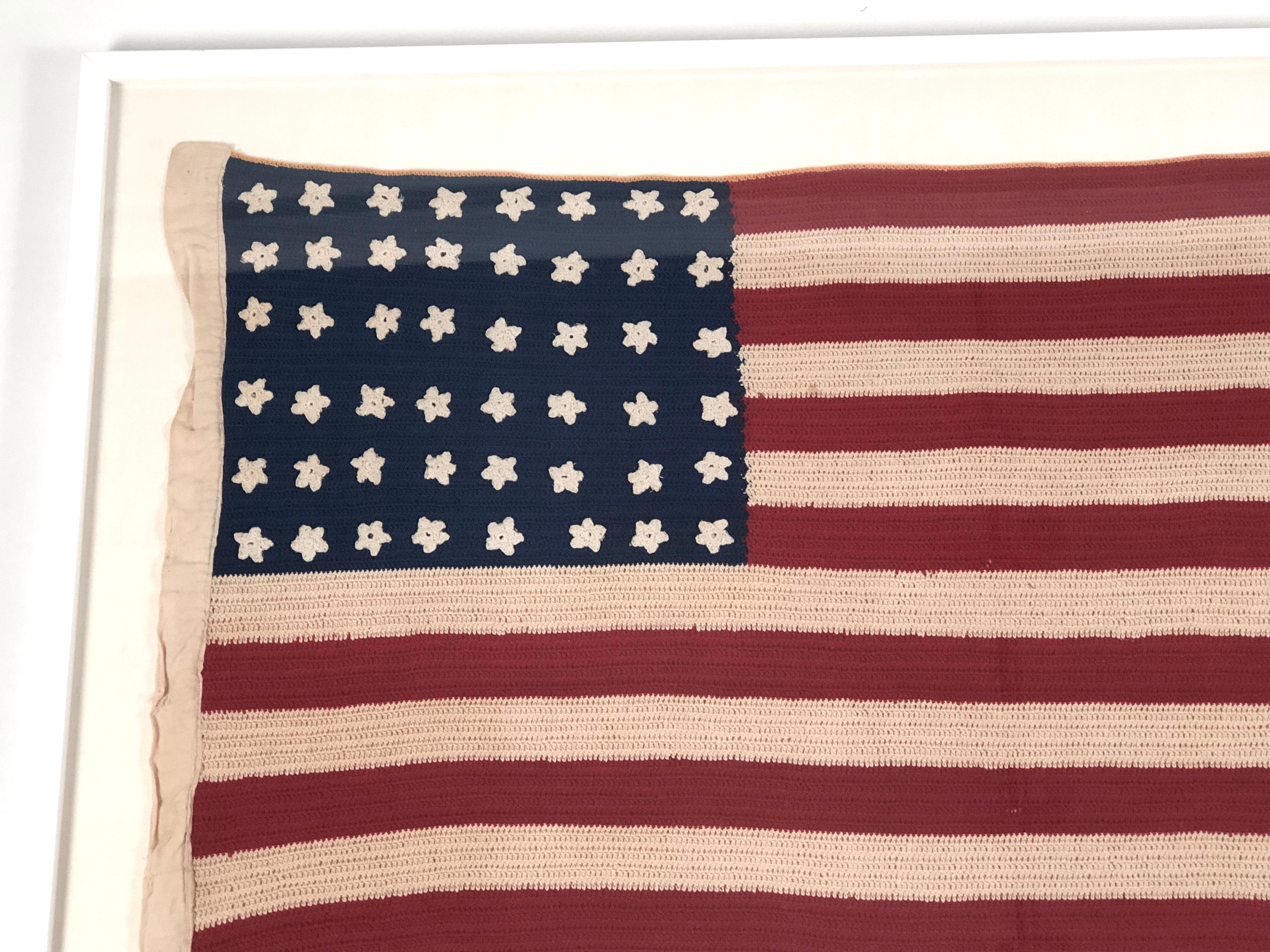 A vintage, hand crocheted 48 star American flag, with newly archival hand sewn mounting on acid free oyster white linen covered matte board, in a white lacquered frame with UV-resistant glass. These flags were made by patriotic women in the 1940s