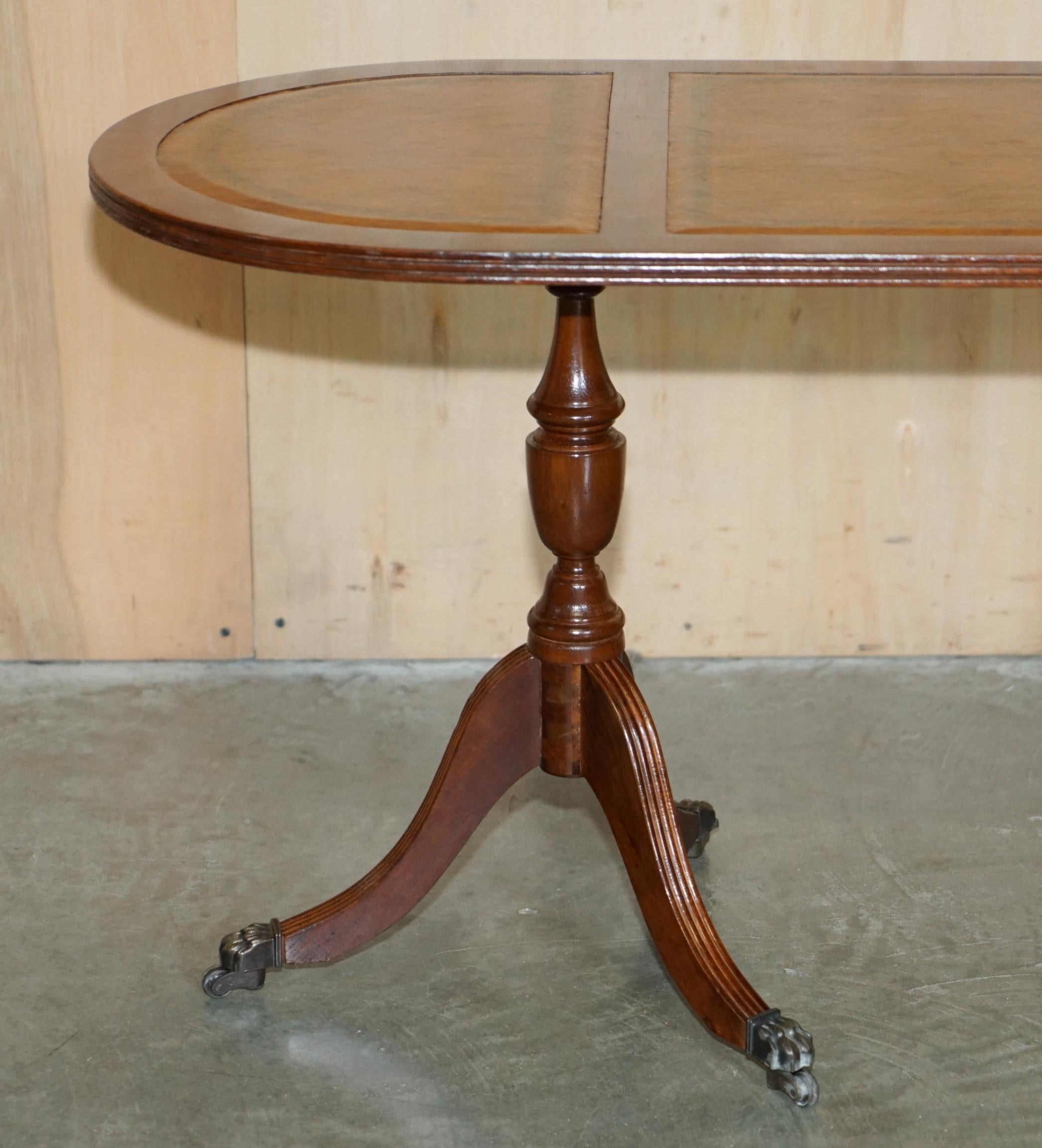 English ViNTAGE HAND DYED AND AGED BROWN LEATHER OVAL COFFEE TABLE WITH LION CASTORS For Sale
