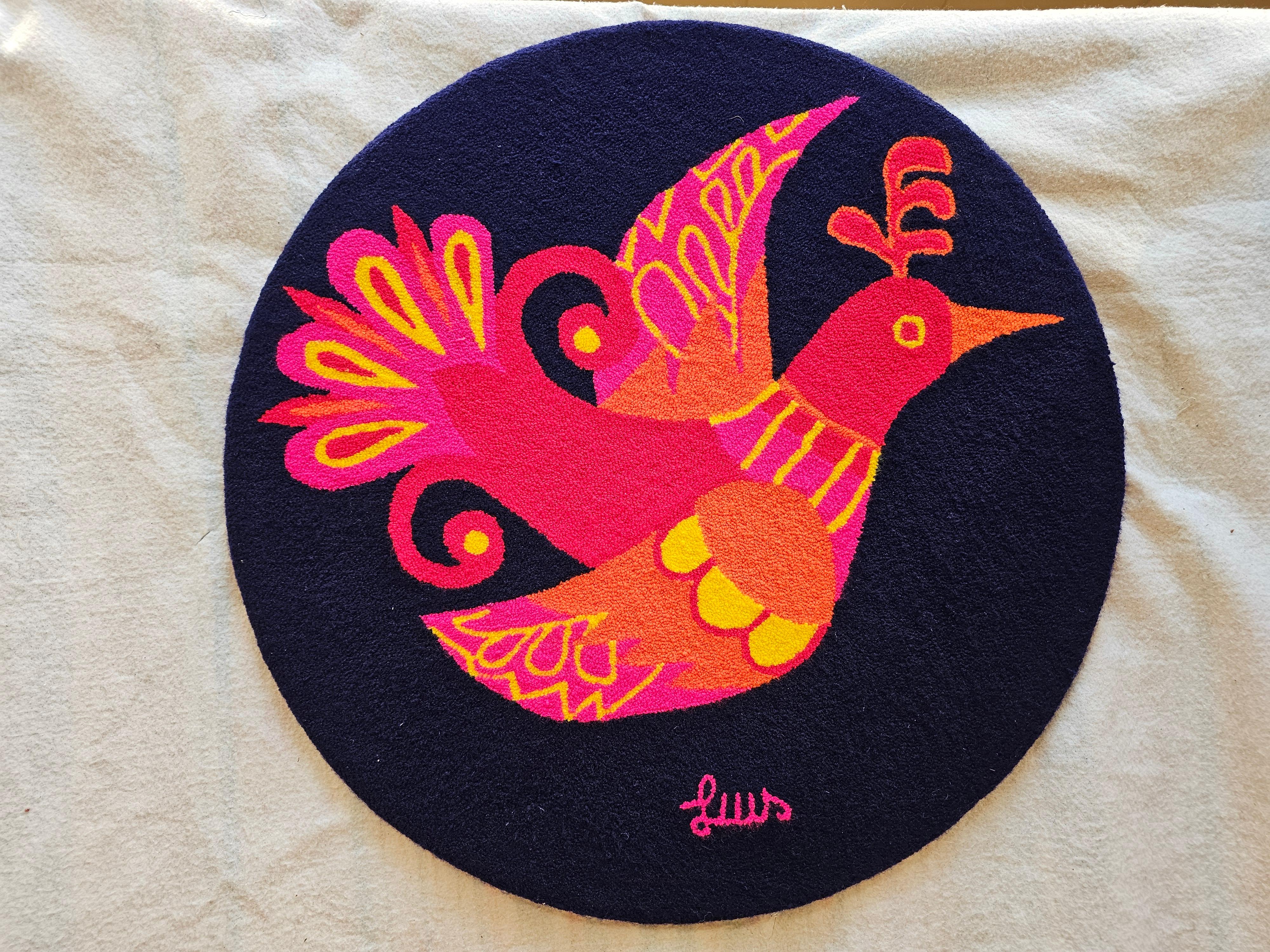 A striking example of mid-20th century textile artistry, this vintage hand-hooked tapestry wall art features a vibrant depiction of a bird rendered in bold shades of red, yellow, crimson, and orange against a deep navy blue background. Rich in