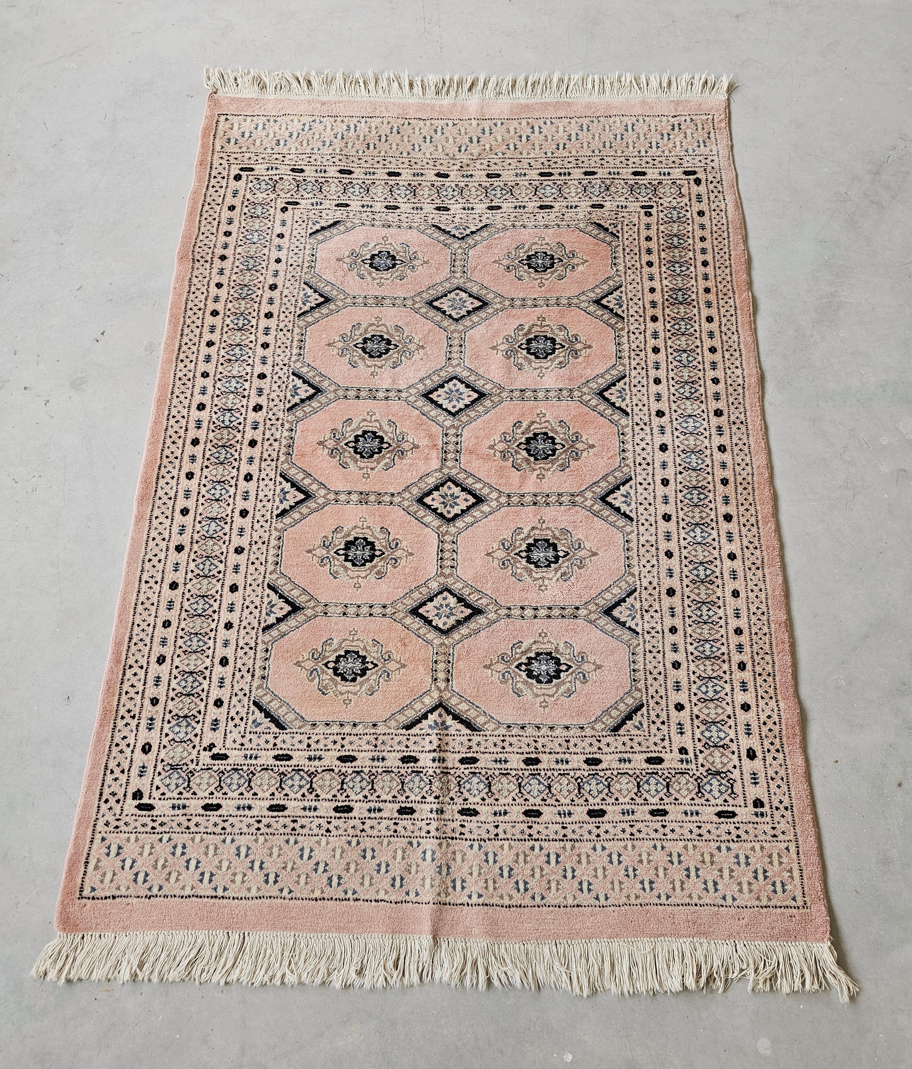 In diesem Angebot finden Sie einen Bokhara-Teppich in einem sehr seltenen puderrosa Ton. Es handelt sich um einen handgeknüpften Teppich aus 100 % Wolle mit einer hohen Knotendichte. Hergestellt in Pakistan, ca. 1950er Jahre.

Sehr guter