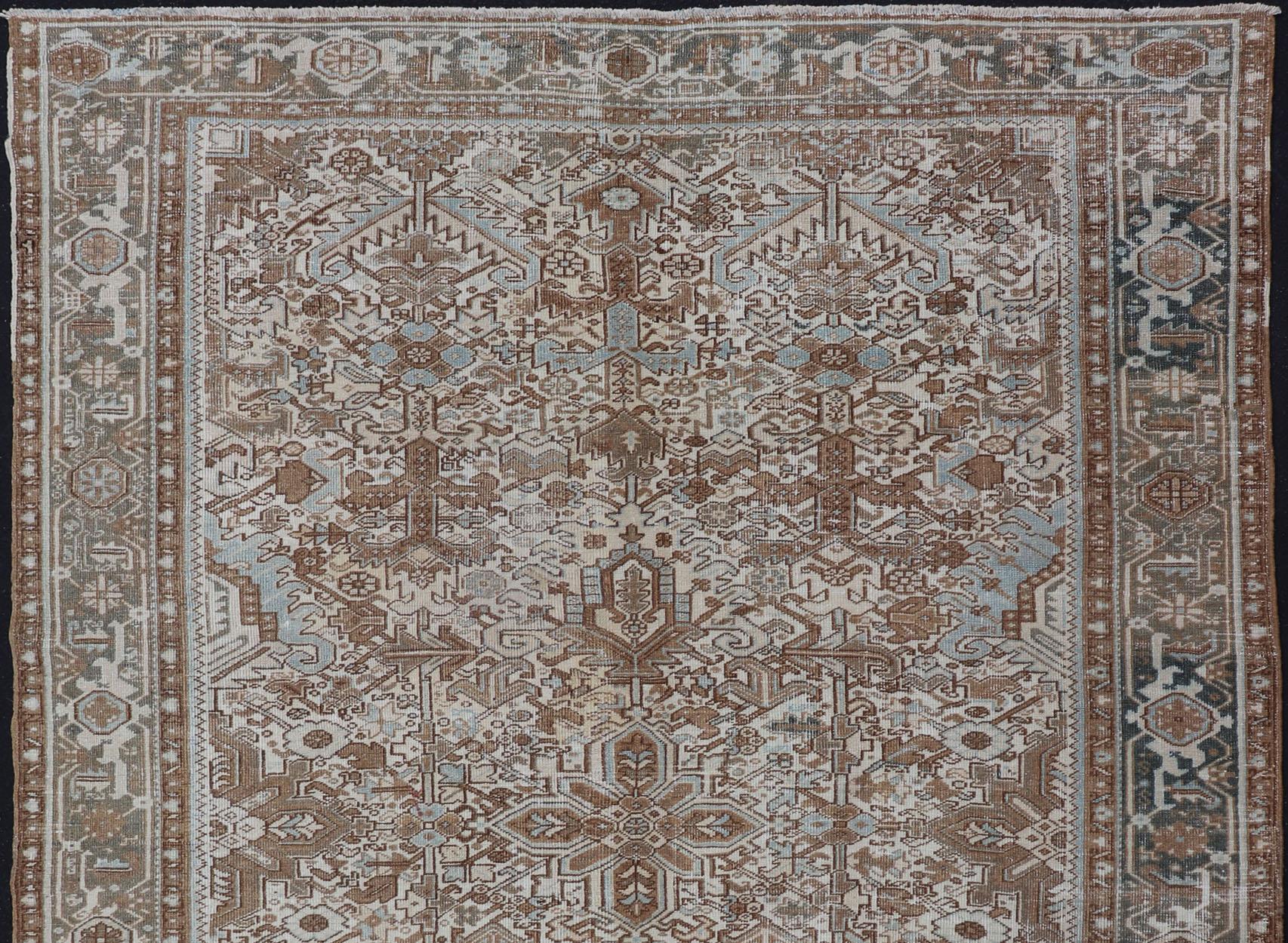 This vintage hand-knotted Persian Heriz rug features an all-over sub-geometric design, enclosed within a complementary, multi-tiered border. The rug is rendered in blues and natural tones; making it a perfect fit for a variety of classic, casual and