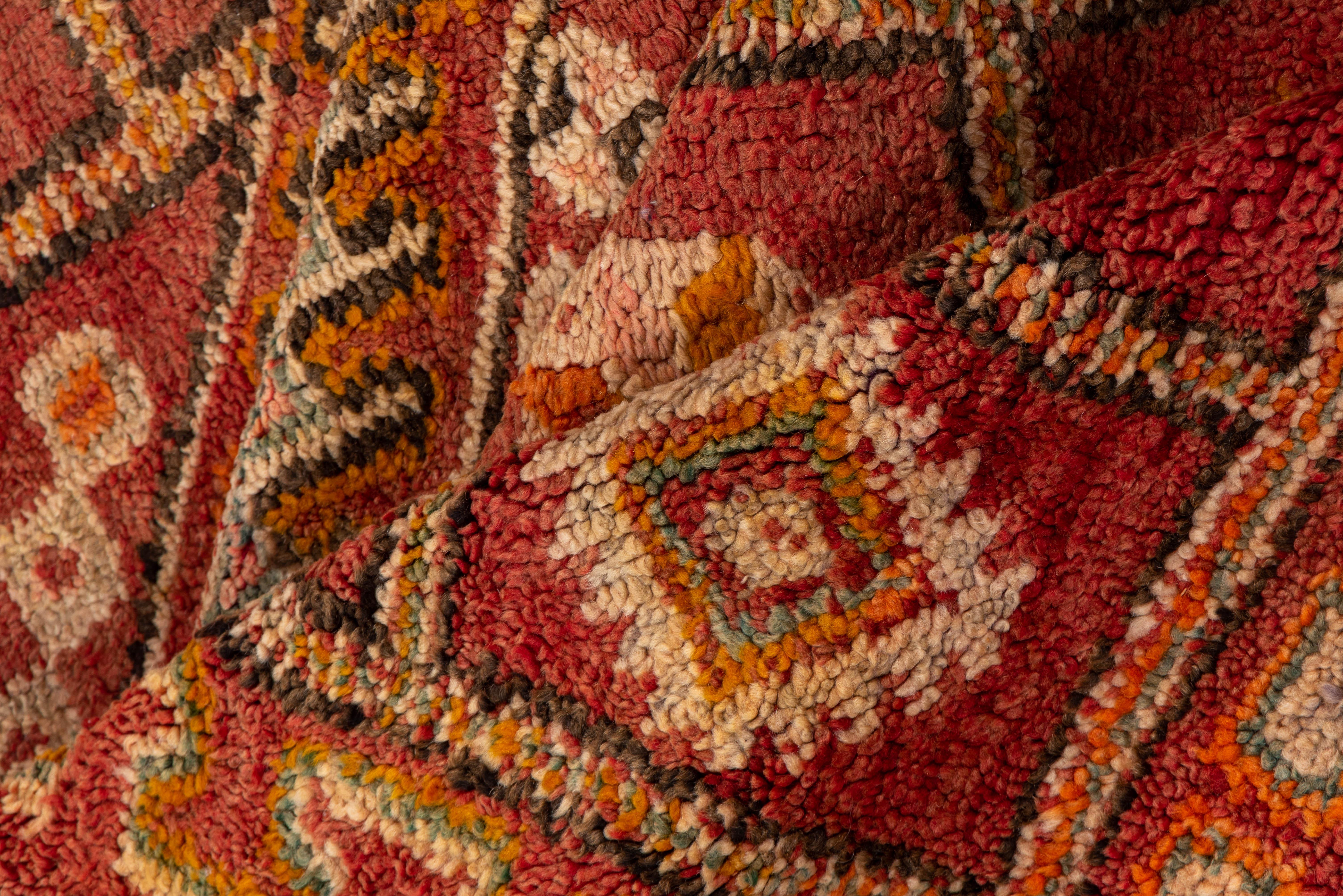 This vintage Moroccan rug showcases a structured grid of floral and geometric forms in a warm palette of brick, ochre, and cream. Three stacked diamond medallions form the centerpiece, framed by stepped borders and classic Berber motifs.