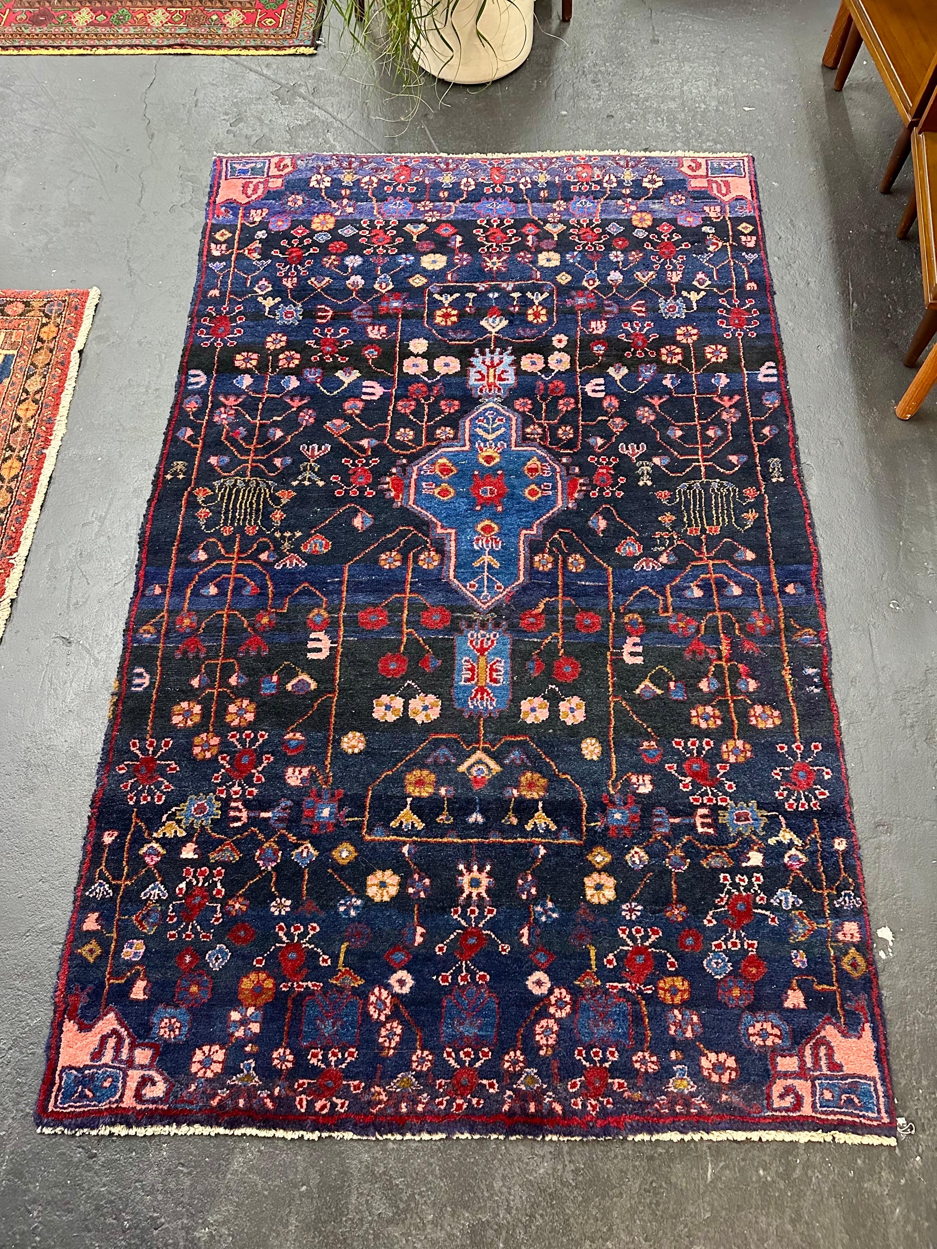 Tappeto vintage in lana annodata a mano. Campo blu navy con un motivo floreale tribale astratto in rosa, rosso, giallo e blu cobalto. Ottime condizioni vintage, solo un minimo di vintage. 7,1L x 4,5W, dimensioni ideali per qualsiasi stanza.

Può
