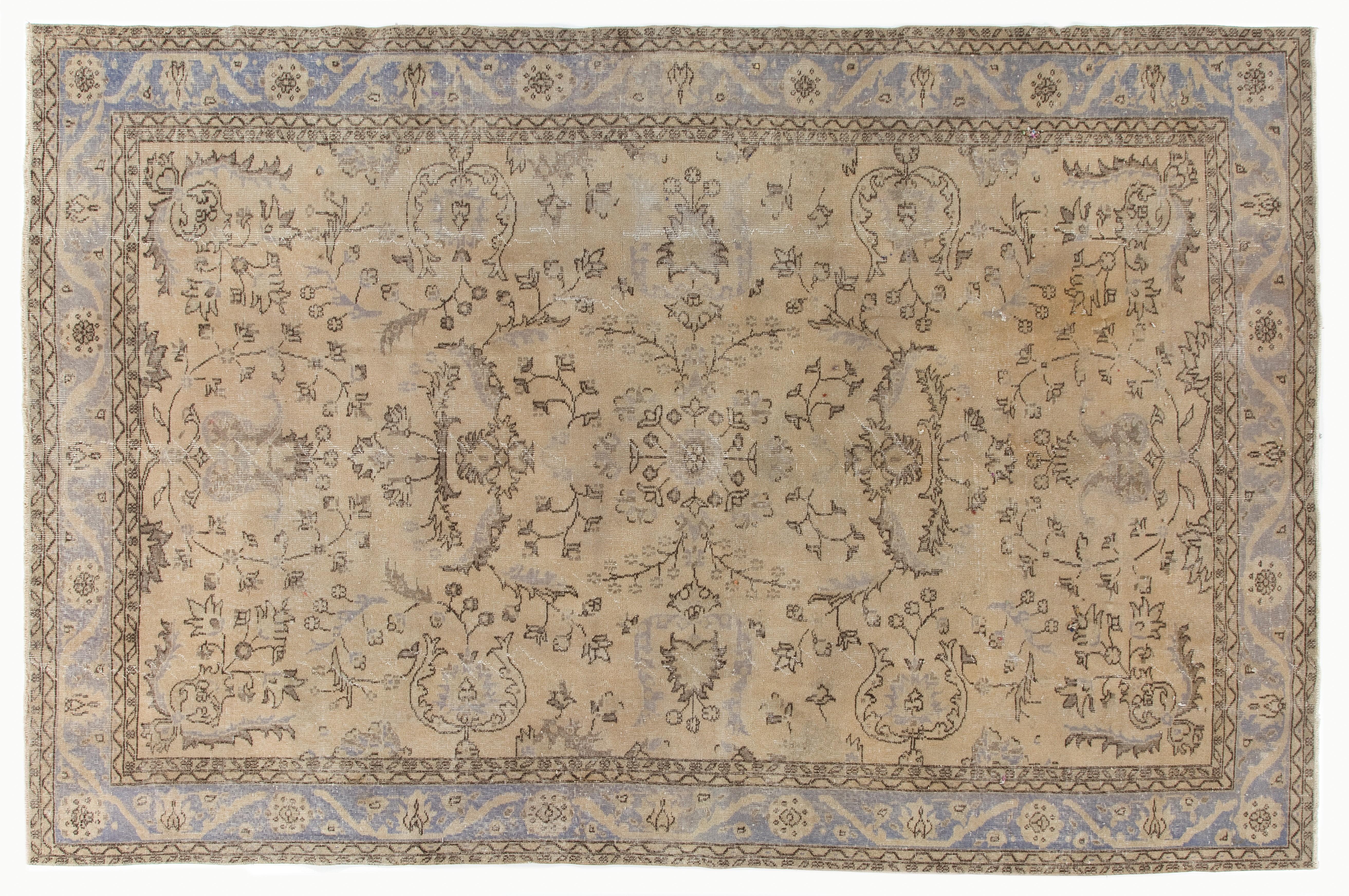 A vintage hand knotted Turkish Oushak rug in a very soft, muted palette of beige, khaki, ecru, tan, fawn and dark steel blue. The rug features two floral medallions at both ends of the field that is filled with symmetrically placed floral vines