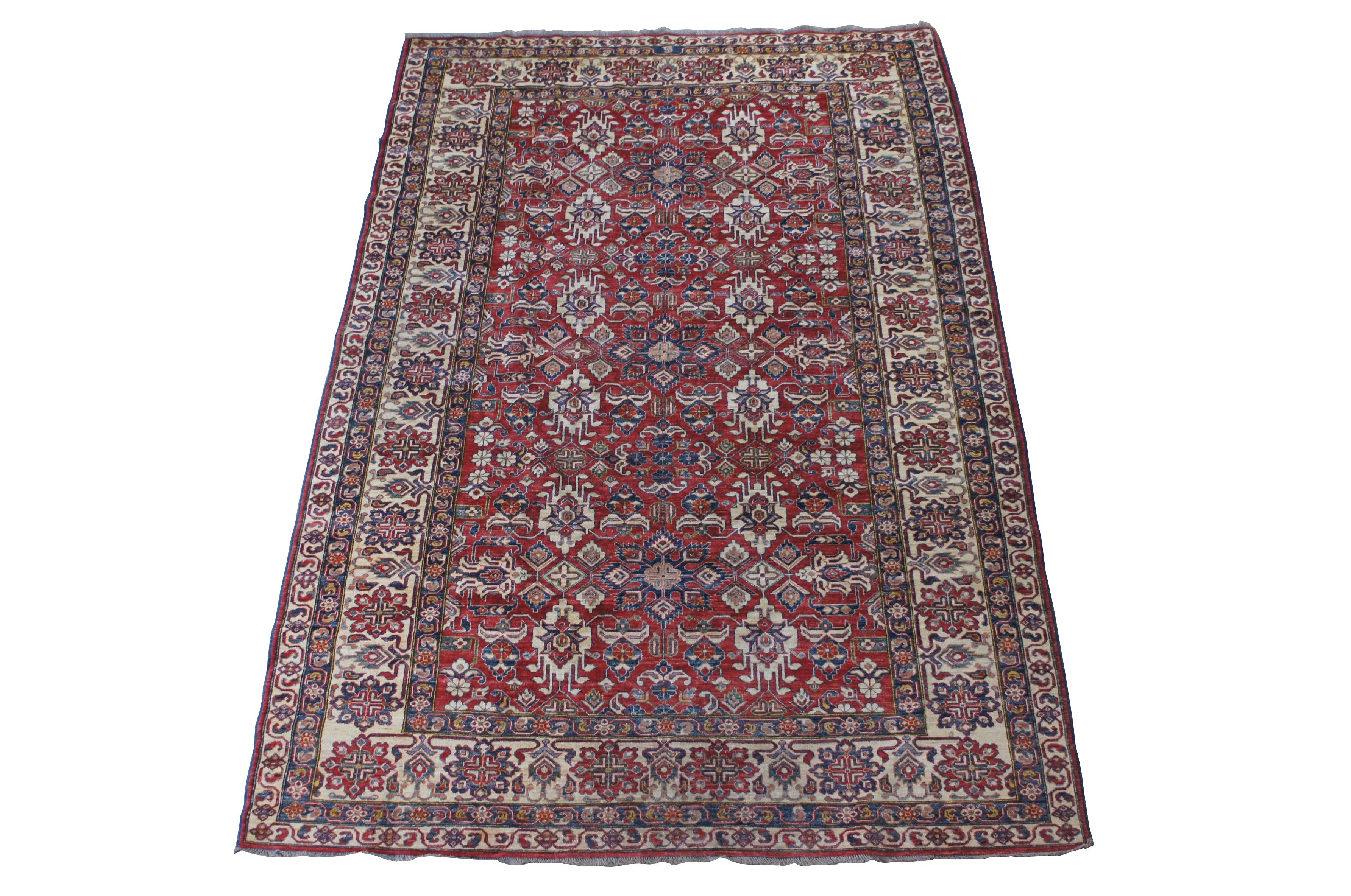 A large and Impressive Pakistani Pak-Persian geometric wool area rug.  Features a hand knotted pile with geometric foliate designs.  The foreground of the rug is red with blue, beige and teal accents.  

Dimensions:
98