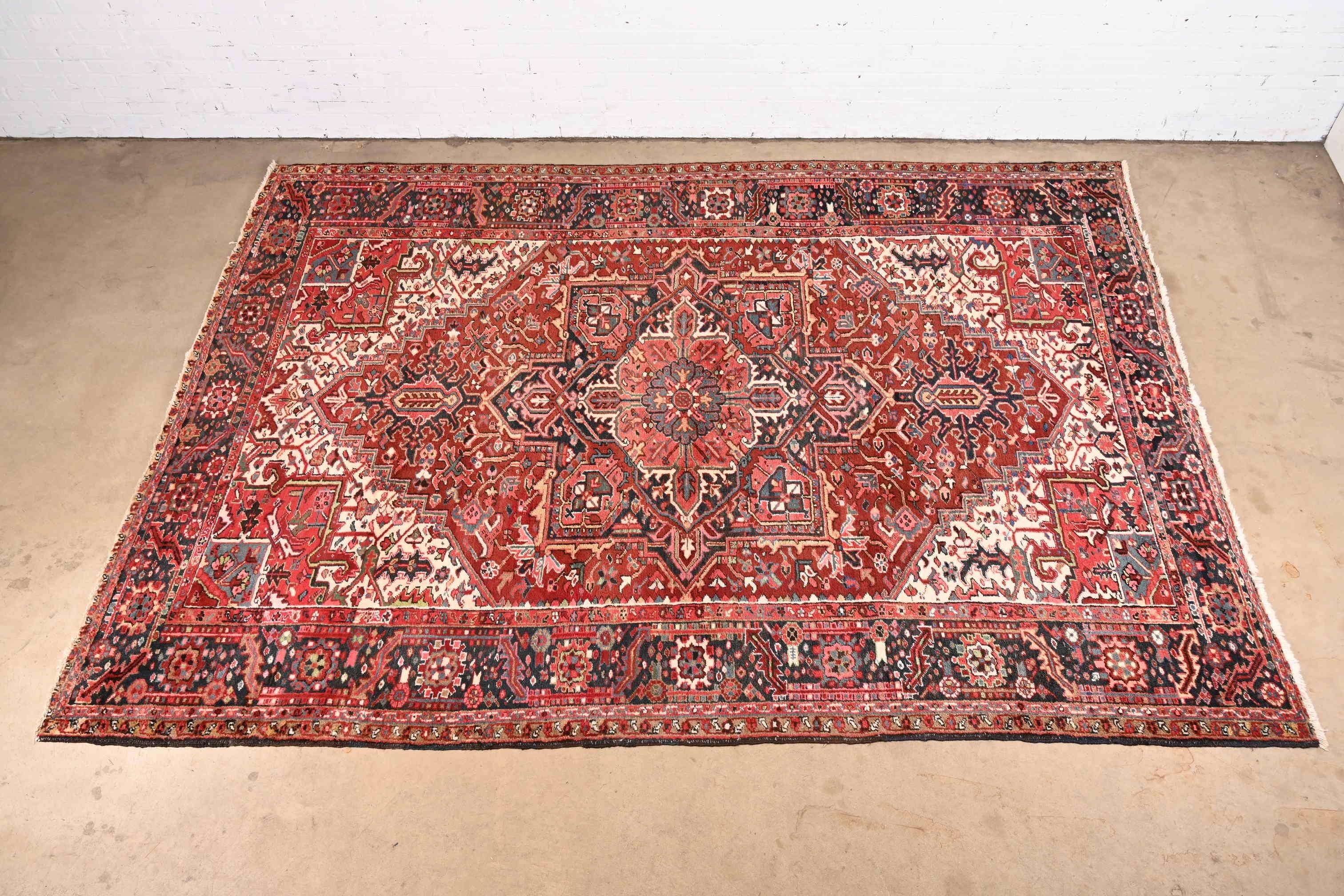 A gorgeous vintage hand knotted Persian Heriz room Size rug

circa 1940s

Classic geometric floral design, with predominant colors in red, blue, and ivory.

Measures: 8'9