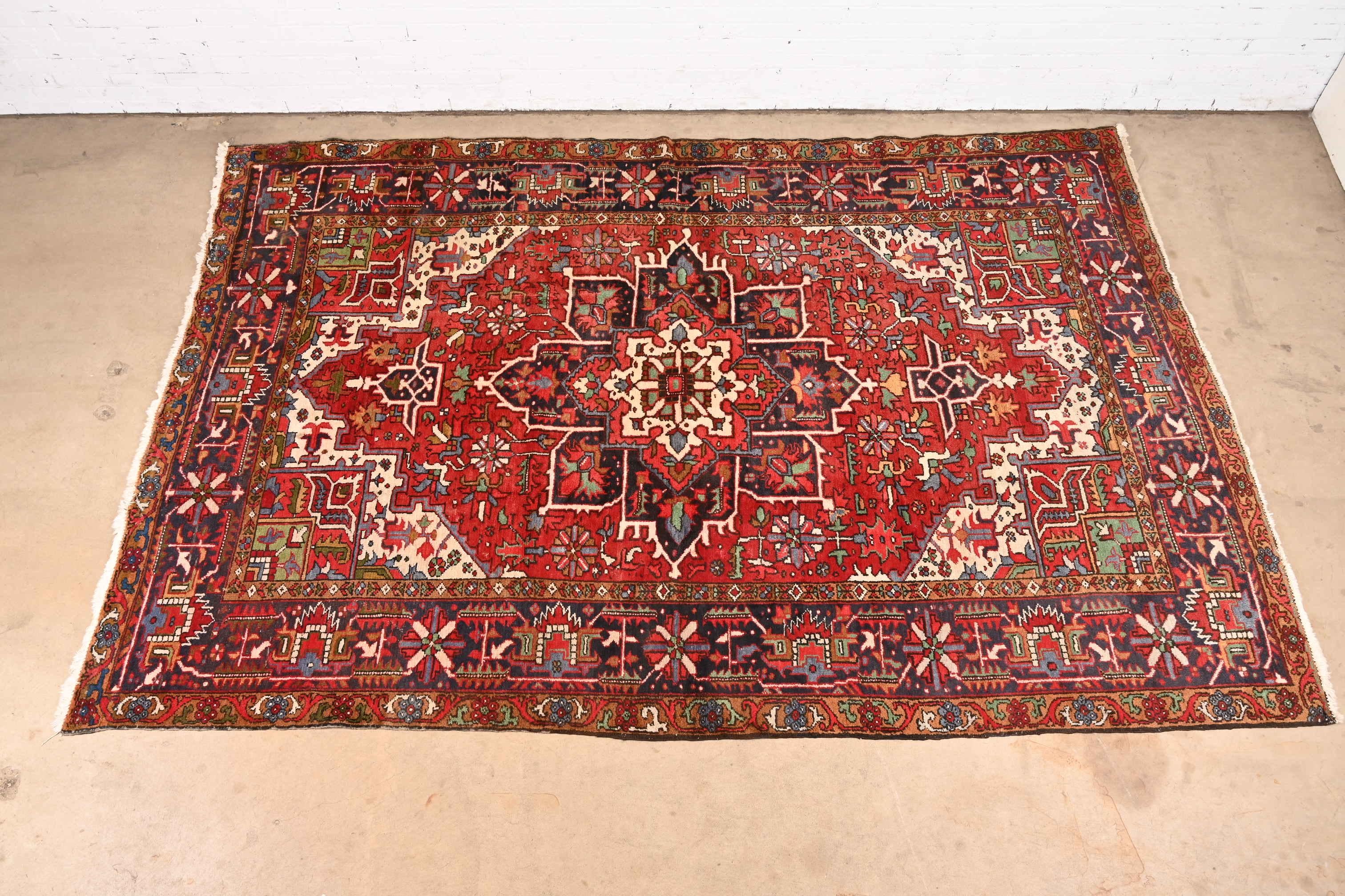 A gorgeous vintage hand-knotted Persian Heriz room size wool rug

Mid-20th Century

Beautiful geometric floral design, with predominant colors in red, blue, gold, green, and ivory.

Measures: 7'8