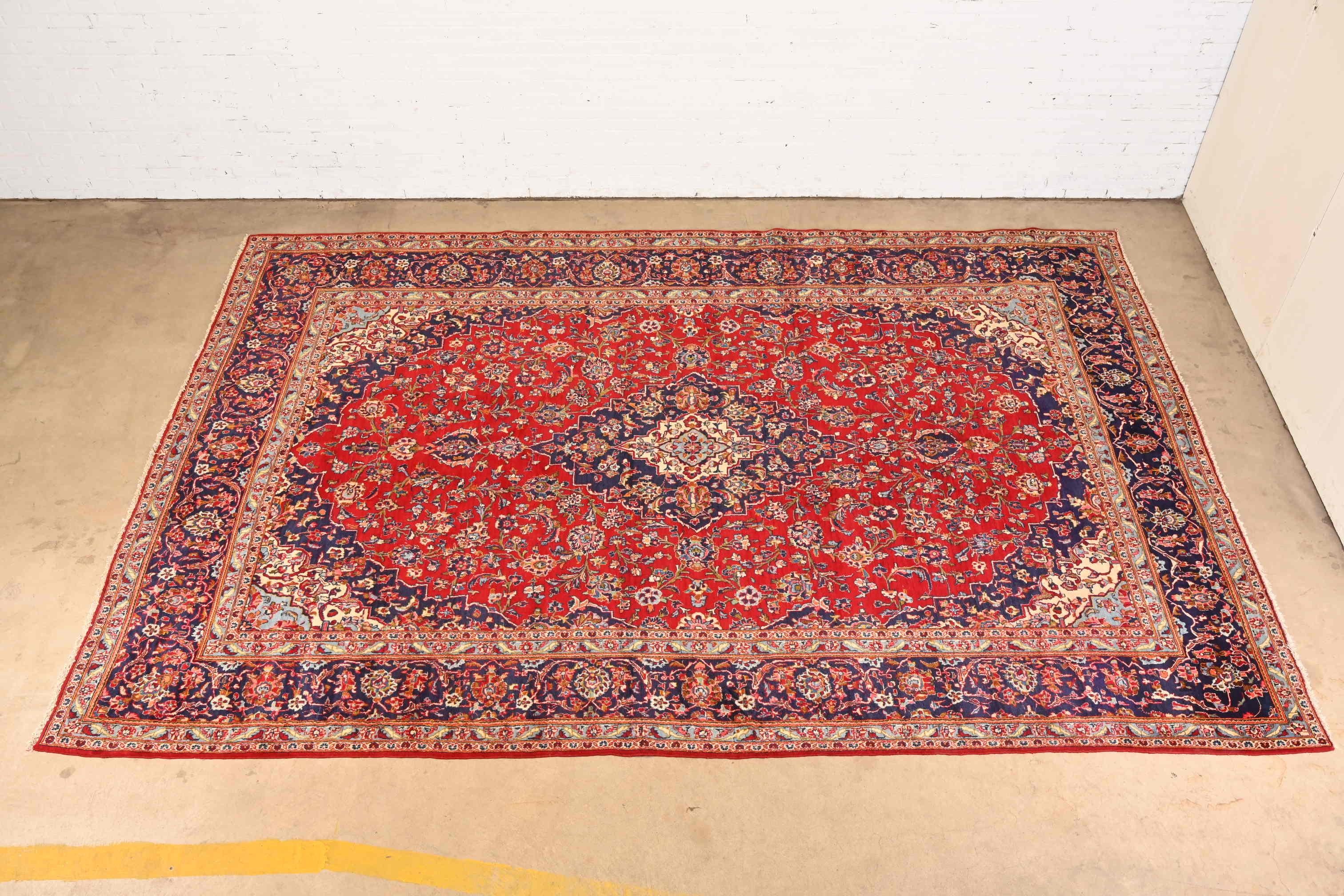 A gorgeous vintage hand-knotted Persian Kashan room size wool rug

Circa Mid-20th Century

Beautiful floral design, with predominant colors in red, blue, and ivory.

Measures: 9'8