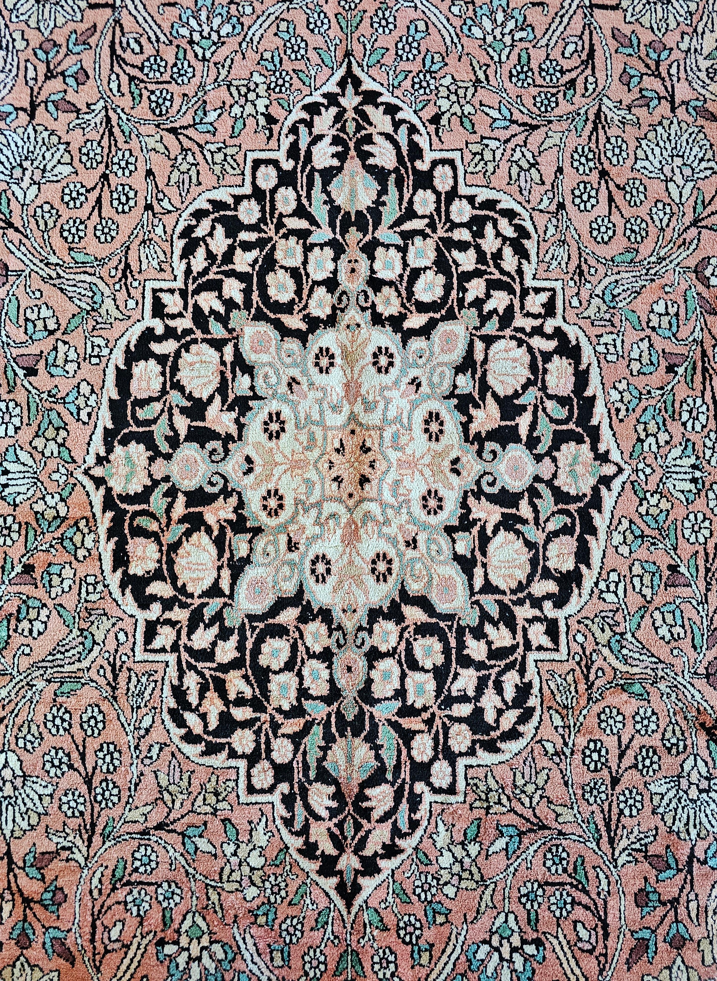 In this listing you will find a beautiful, elegant vintage rug done in silk on cotton base. The rug was hand-knotted in pink silk, with black and off-white areas. It features rich floral pattern with occasional motif of a bird. Made in Pakistan in