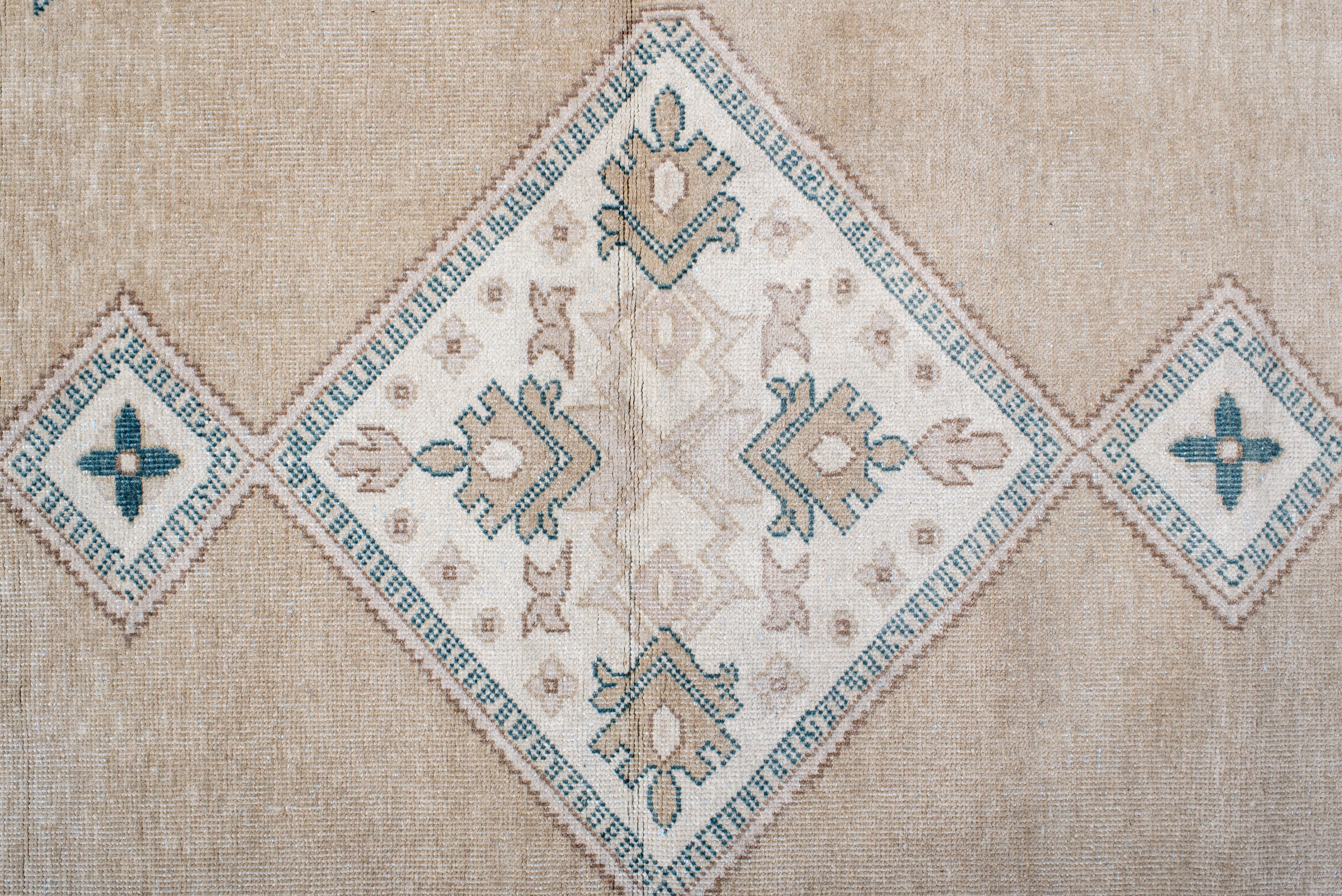 Dieser handgeknüpfte Sivas-Teppich im Vintage-Stil zeichnet sich durch eine anmutige Reihe geometrischer Rautenmedaillons aus, die sich über ein weiches taupefarbenes Feld erstrecken, das durch knackige Details in Teal und Elfenbein akzentuiert