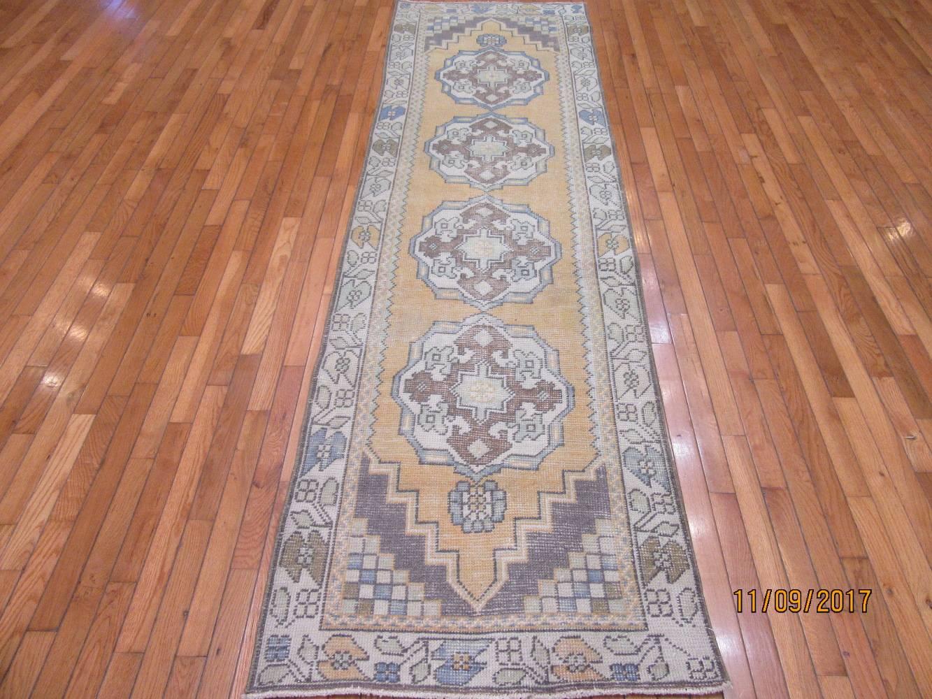 This is a vintage hand-knotted rug from the Anatolian region of Turkey. It is made with wool on a cotton foundation. The rug measures 2' 9'' x 9' 5'' which make it fit any short hall or space throughout the house or office. It has a semi distressed