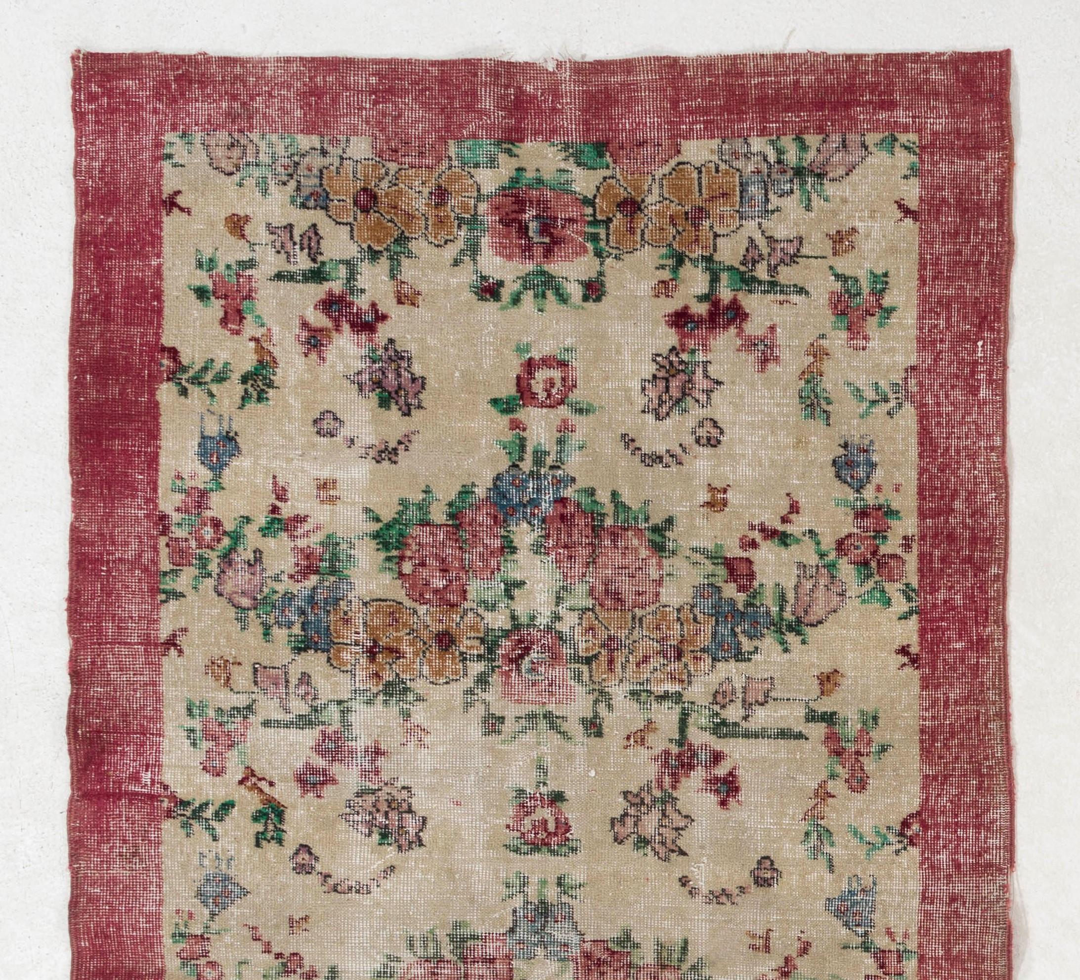 Dieser handgeknüpfte türkische Teppich aus den 1960er Jahren zeigt ein üppiges Blumenmuster in Rot, Rosa, Gold und Blau auf einem elfenbeinfarbenen Feld und eine einfarbige Hauptbordüre in Rot.

Der Teppich hat einen niedrigen Wollflor auf einer