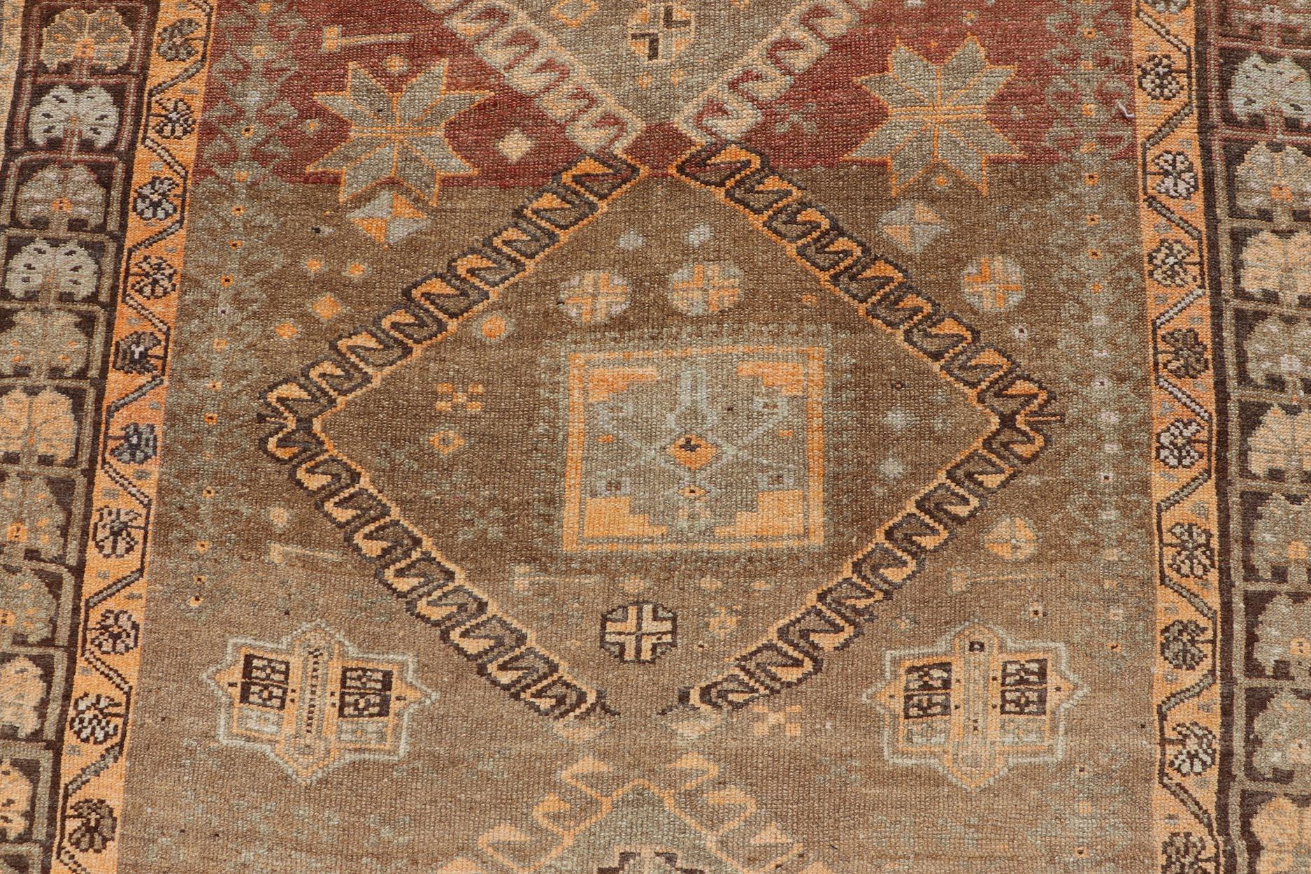 This antique Turkish Kars rug has been hand-knotted in wool and features an all-over, sub-geometric diamond design rendered in orange and earthy tones. A complementary, multi-tiered border encompasses the entirety of the piece; making it a marvelous
