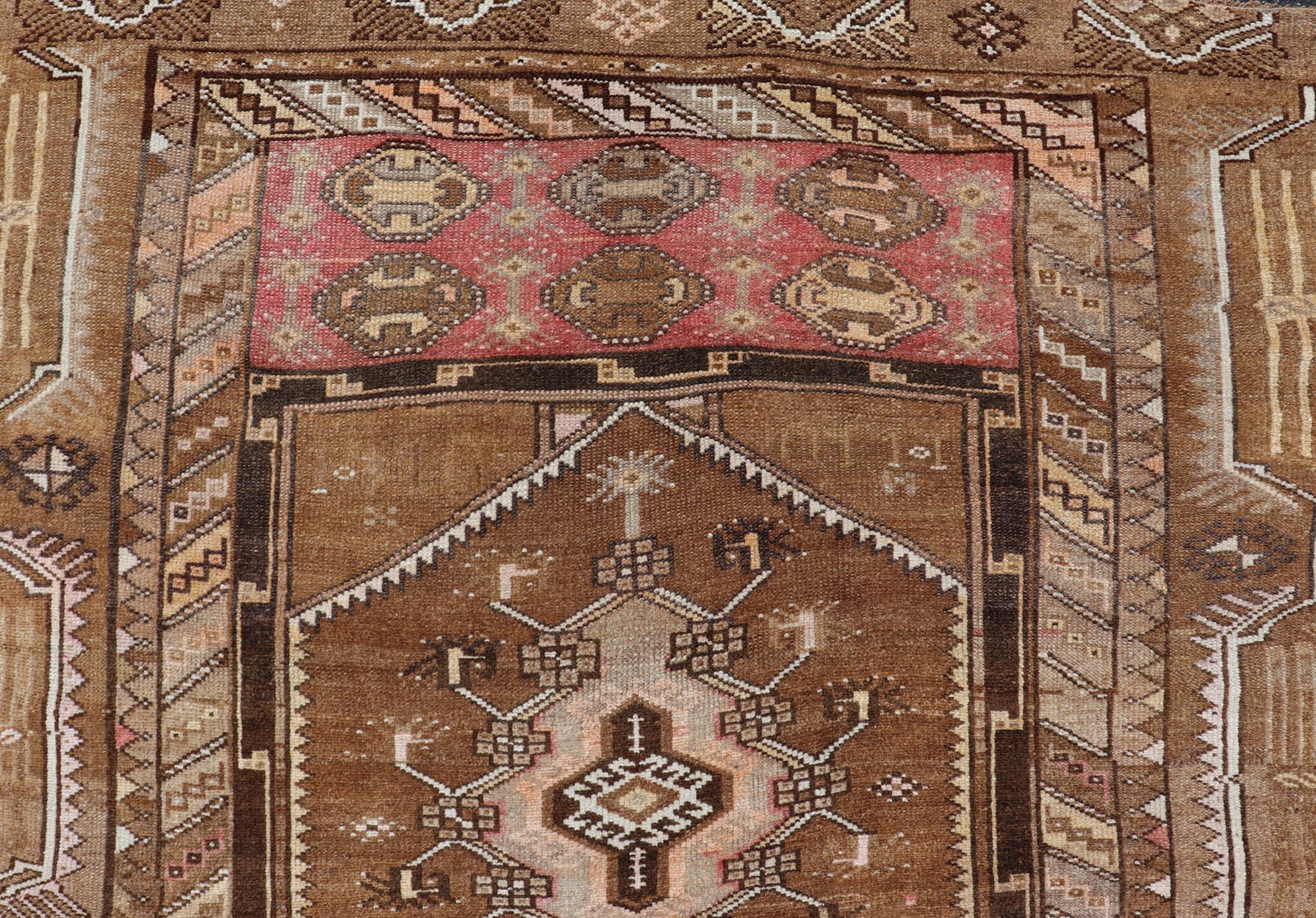 This vintage Turkish Kars gallery rug has been hand-knotted in wool and features a sub-geometric medallion design rendered in multicolor. A complementary, multi-tiered border encompasses the entirety of the piece; making it a marvelous fit for a