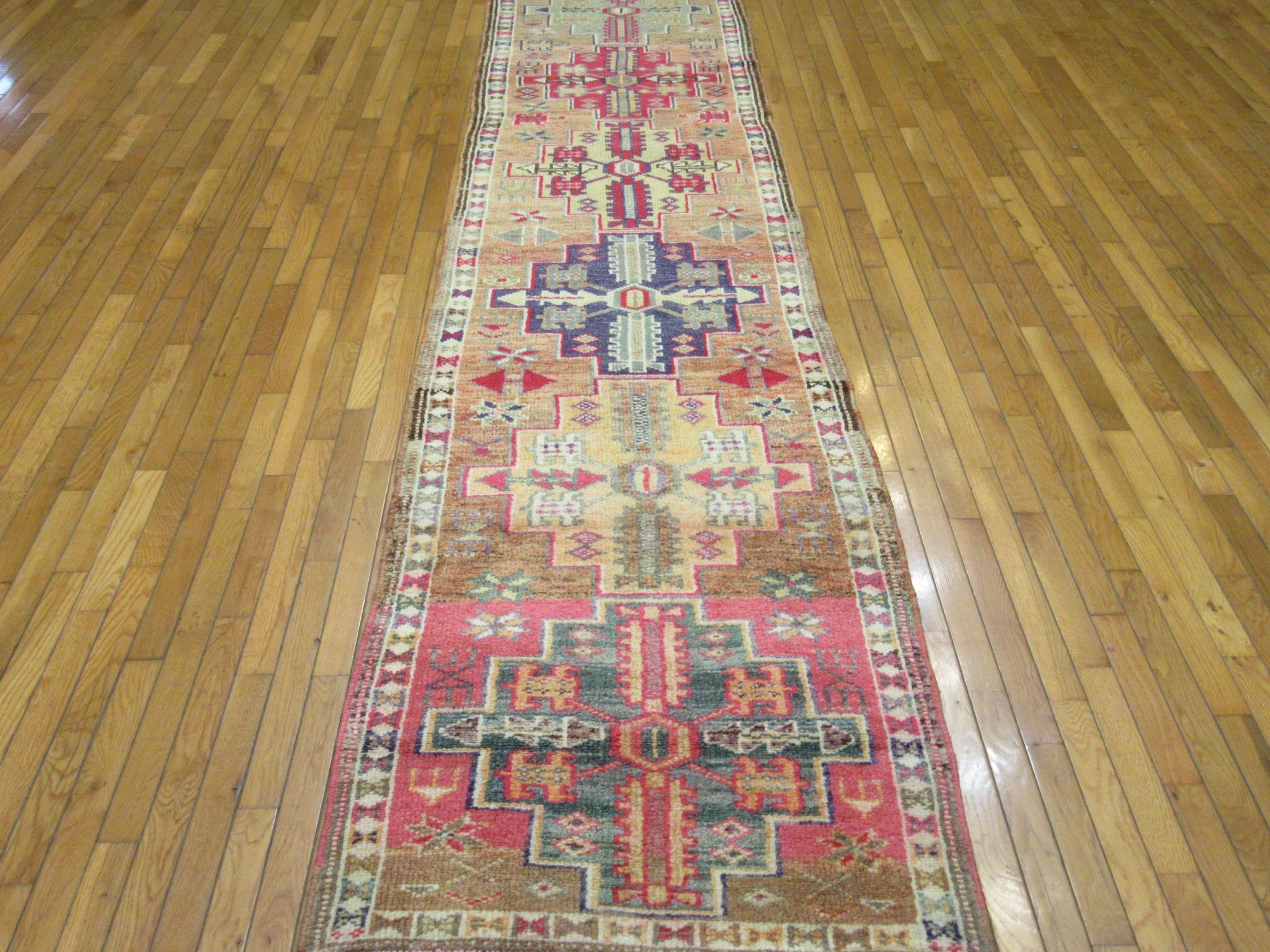 This is a vintage hand knotted Turkish runner rug from the Anatolian region. It is made with wool in a simple tribal pattern. This runner would enhance the look of any hall or space. It measures 2' 9'' x 13' 9'' and in great condition.