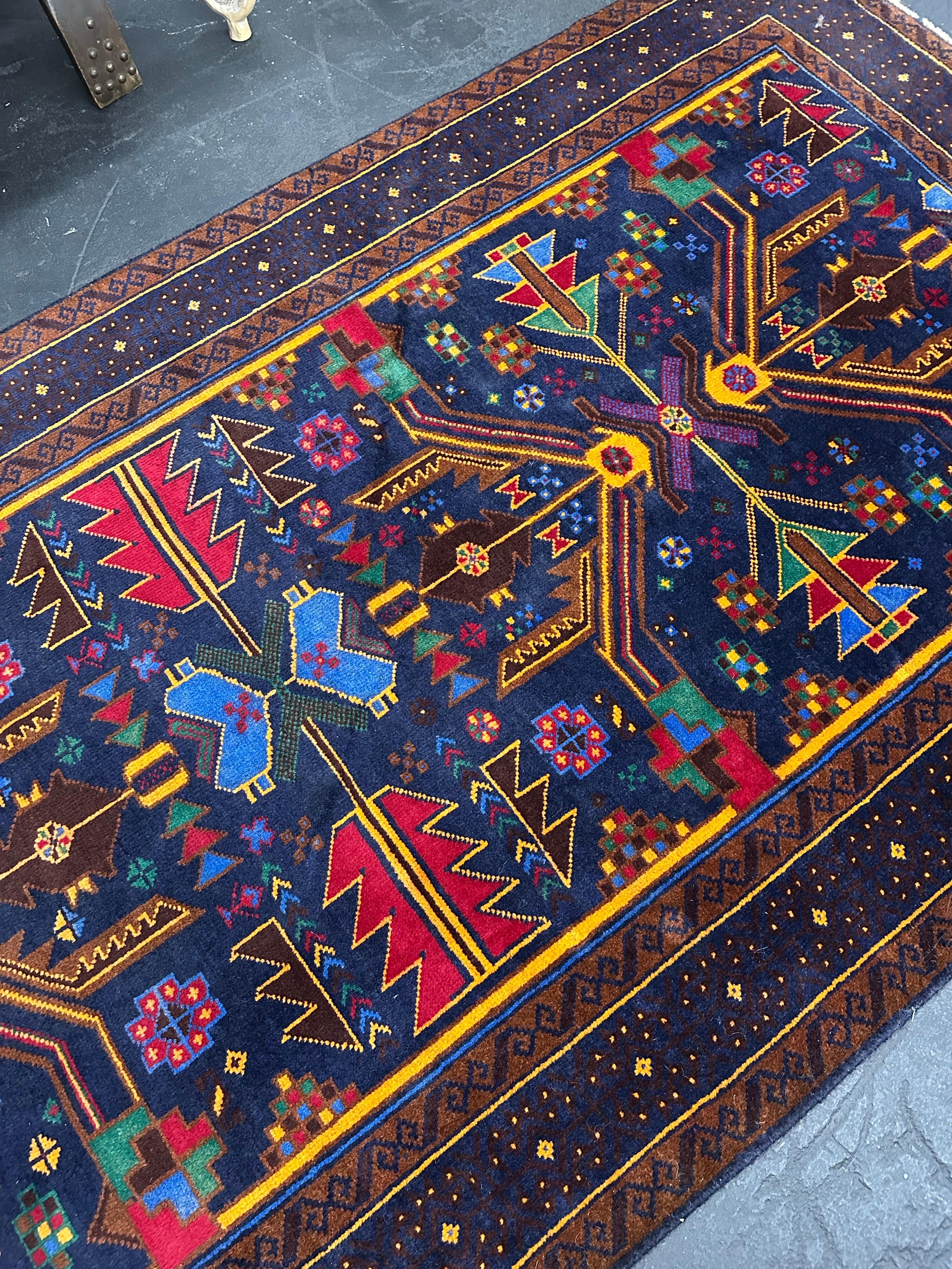 Tapis d'accent vintage en laine nouée à la main, fabriqué par la tribe Rugs du nord-ouest de l'Afghanistan. Des couleurs riches et profondes sur un champ bleu indigo. Motif floral géométrique tribal en vert, rouge, jaune, violet et marron. Tissage