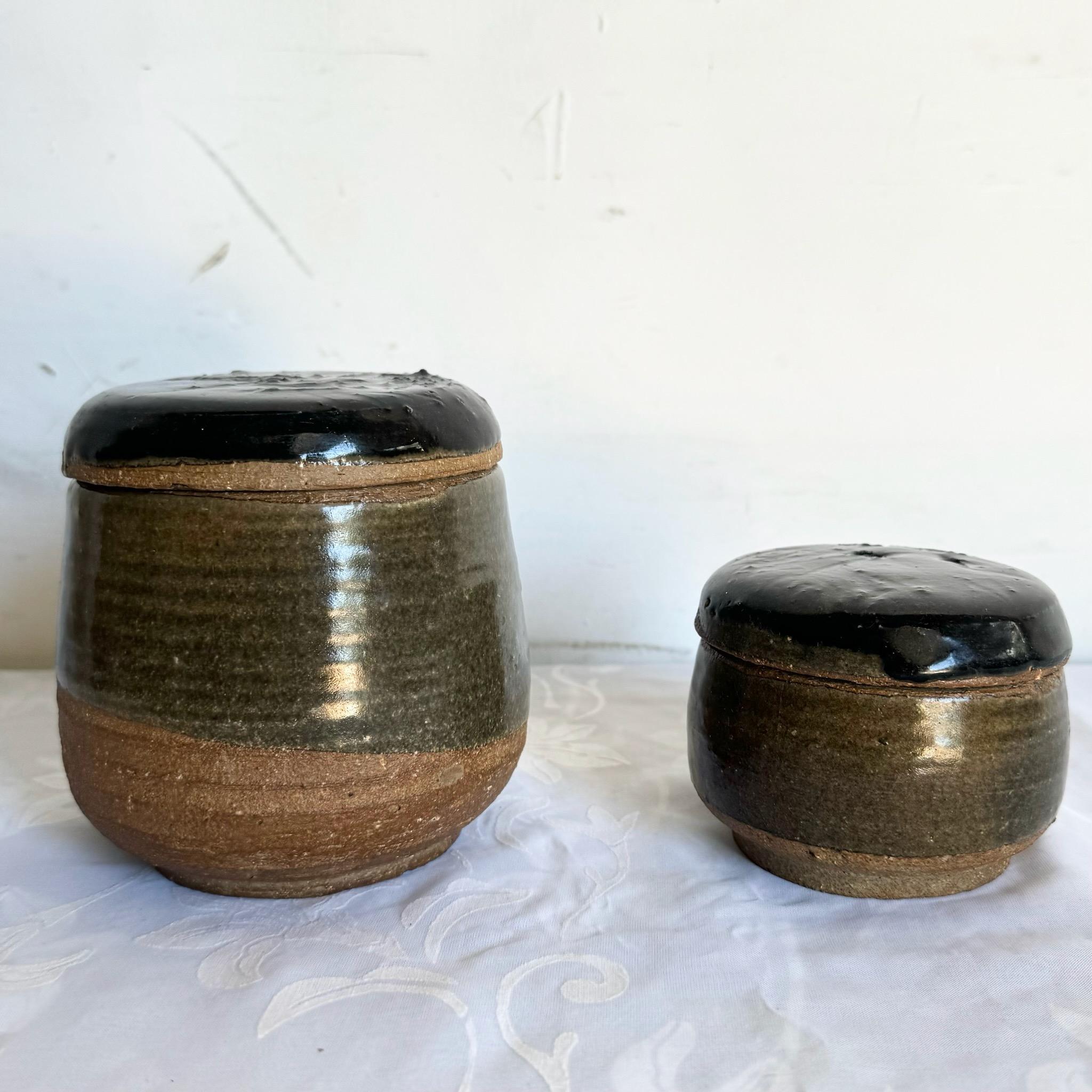 This set of two vintage handmade pottery jars showcases artisan craftsmanship with earthy tones and rustic charm. Each jar comes with a lid, perfect for storing small items while adding a natural, handmade touch to your home decor.

