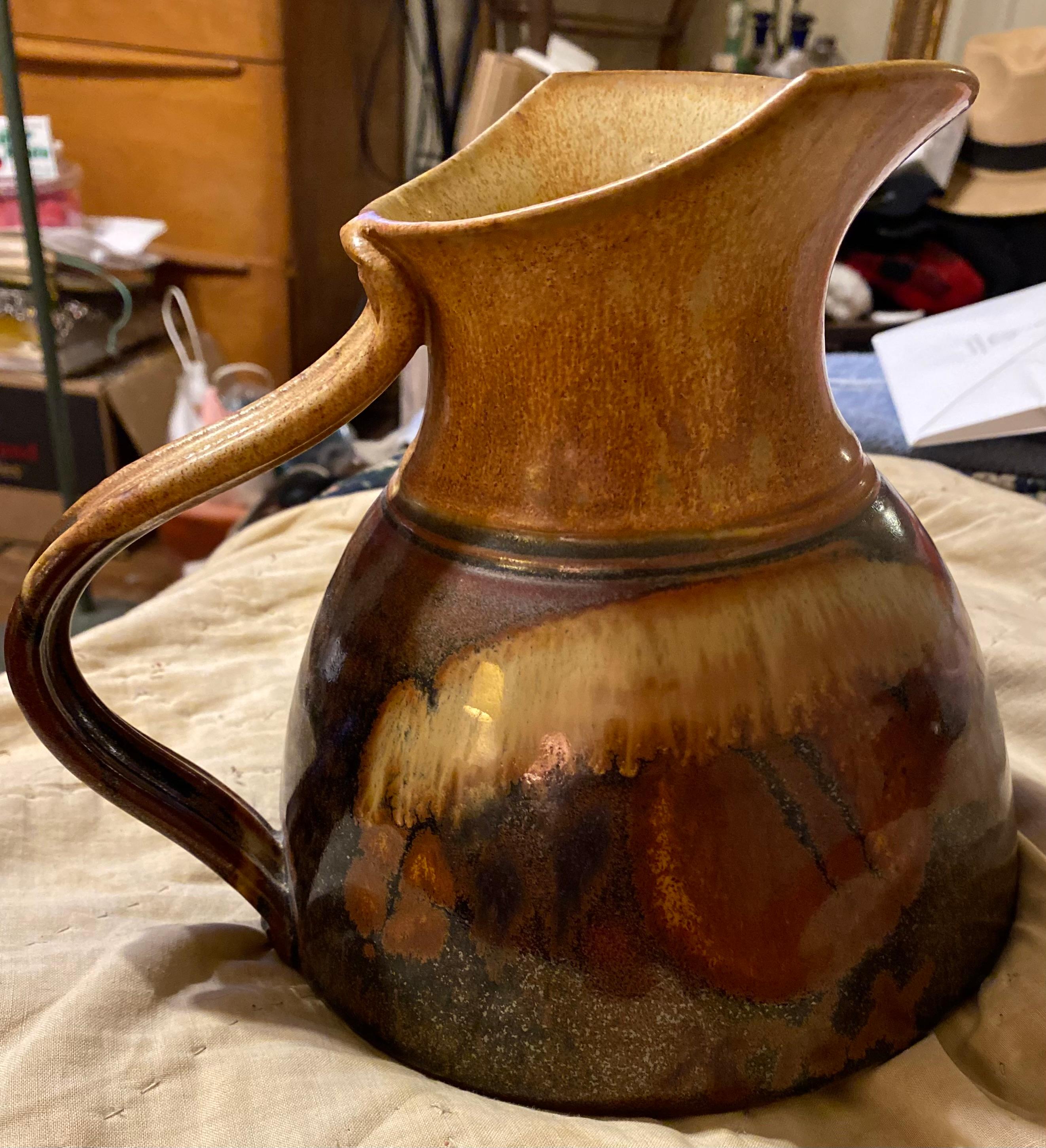 A large hand thrown stoneware water pitcher with a very large spout...signed on the bottom by the artist. Richard Stafford Bainbridge Island Washington. Brown stoneware with a black glaze.